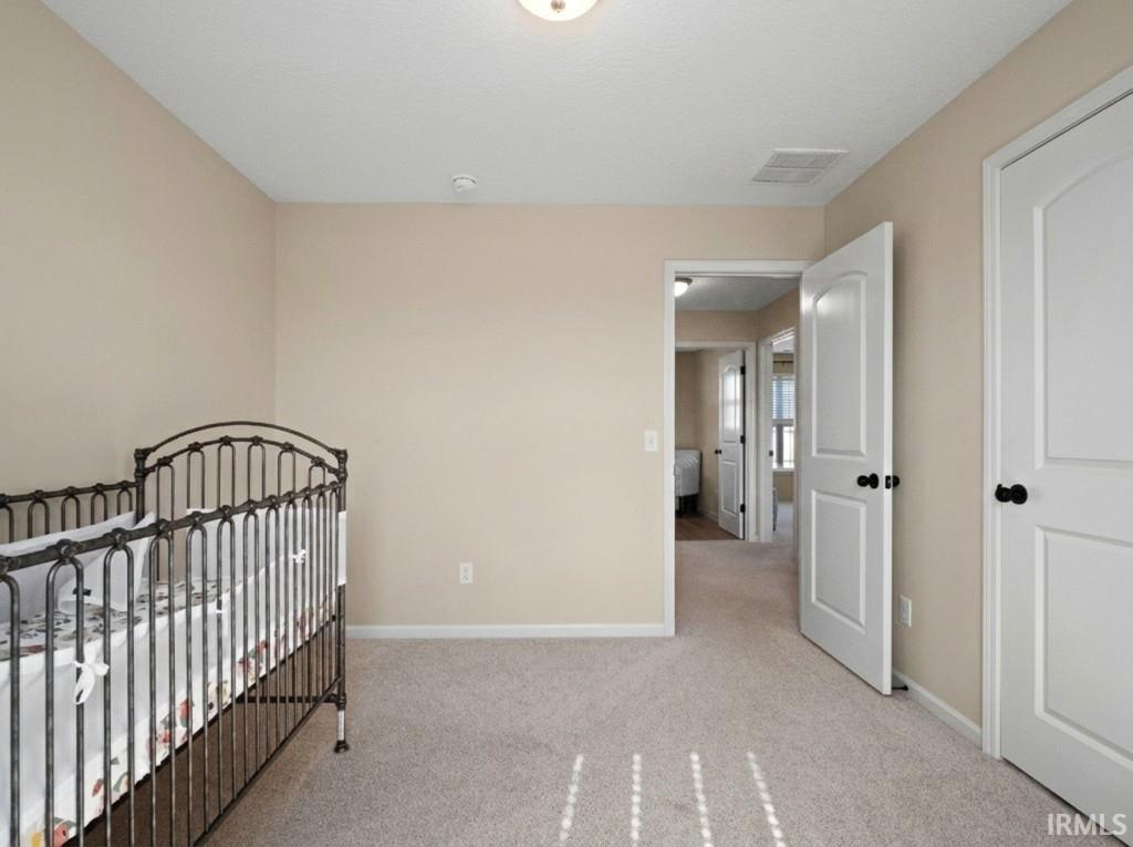 Bedroom featuring a crib and light carpet