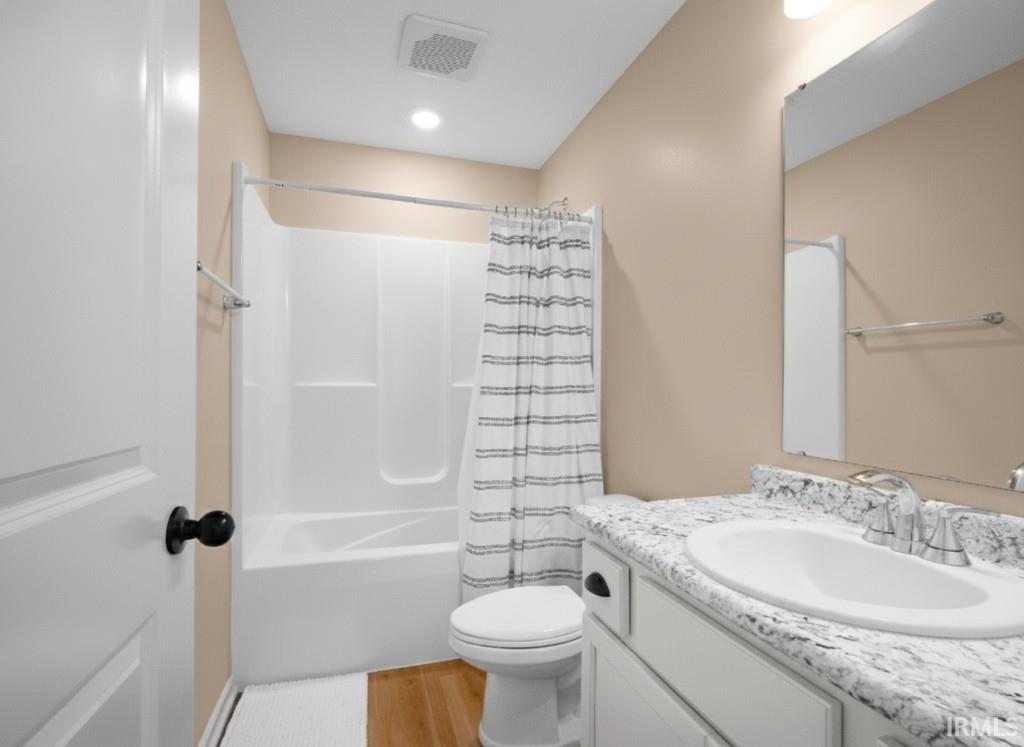 Bathroom featuring vanity, shower / bath combo with shower curtain, and light wood-style floors