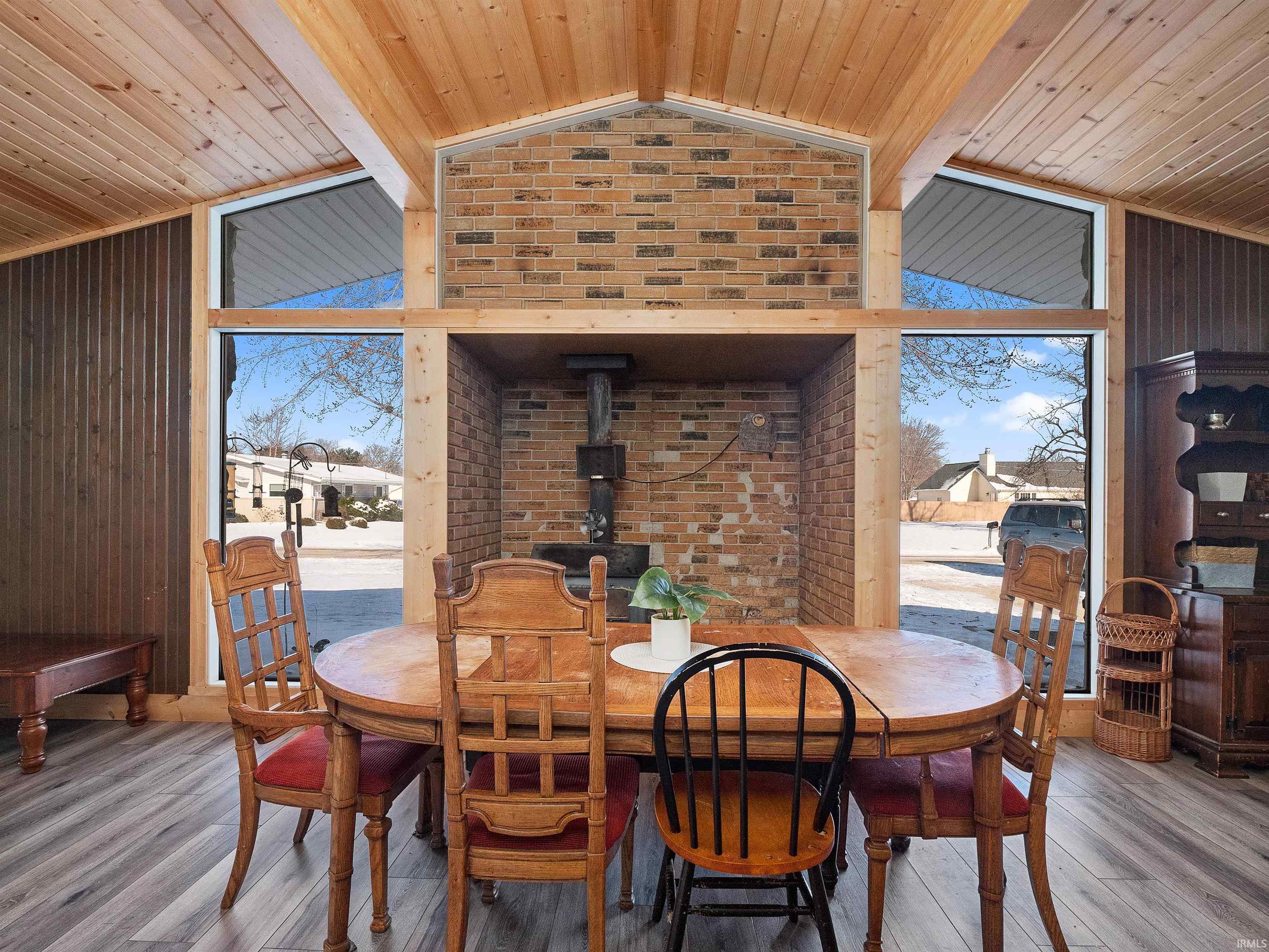 Dining space featuring a wood stove, lofted ceiling, wooden ceiling, plenty of natural light, and wood finished floors