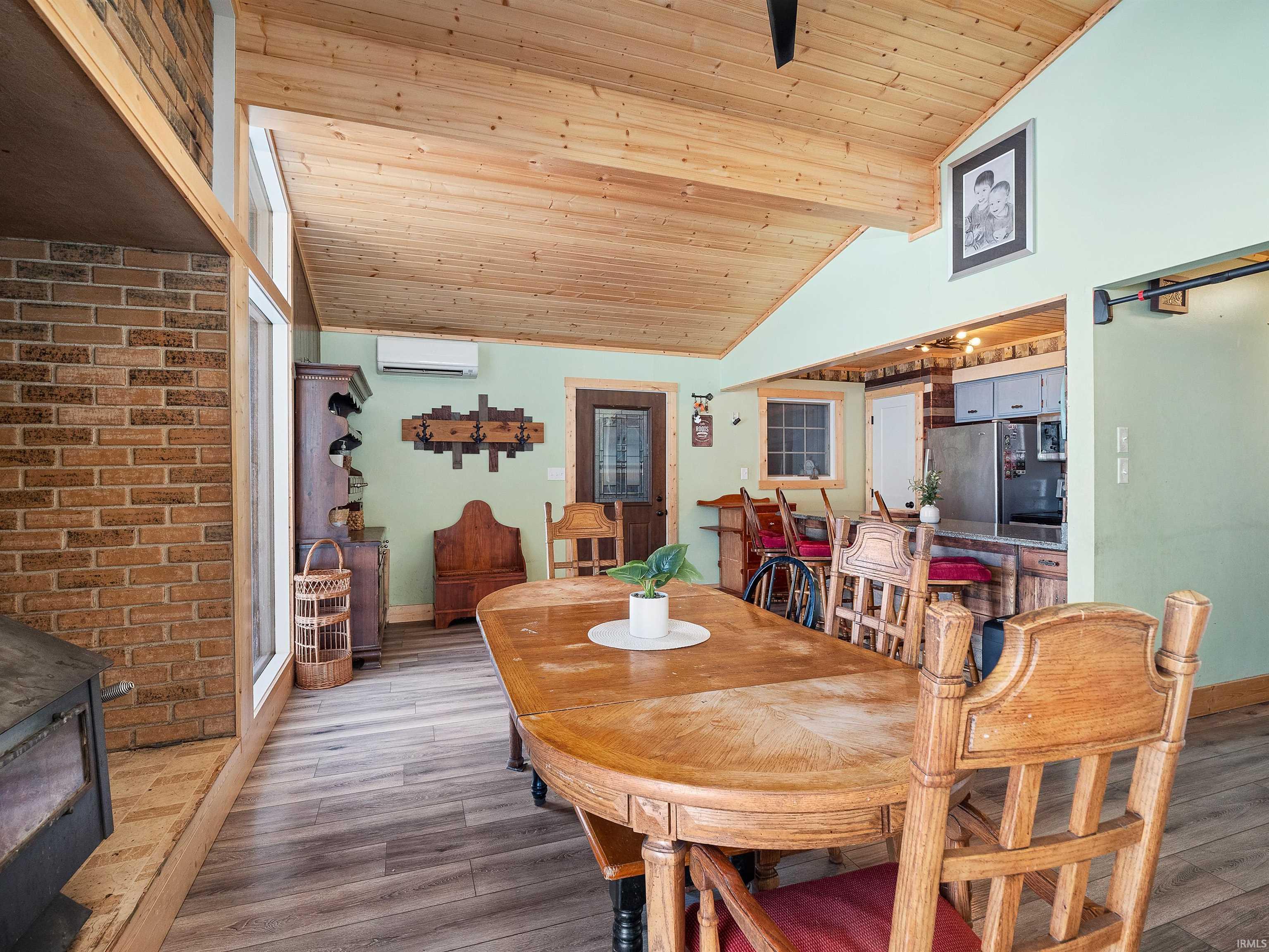 Dining room featuring a wood stove, wooden ceiling, light wood finished floors, and lofted ceiling