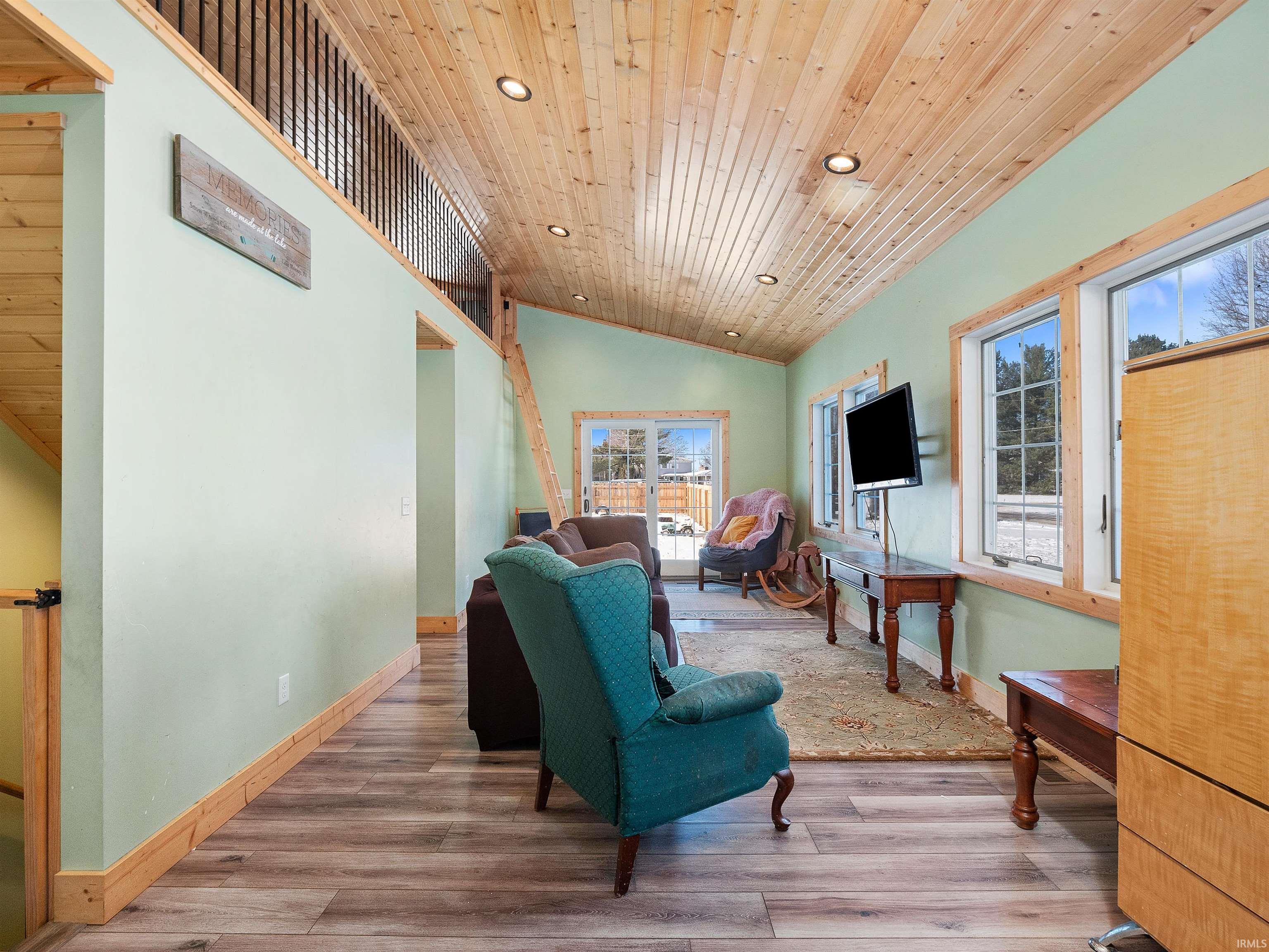 Living room featuring lofted ceiling, light wood-style floors, wood ceiling, and recessed lighting