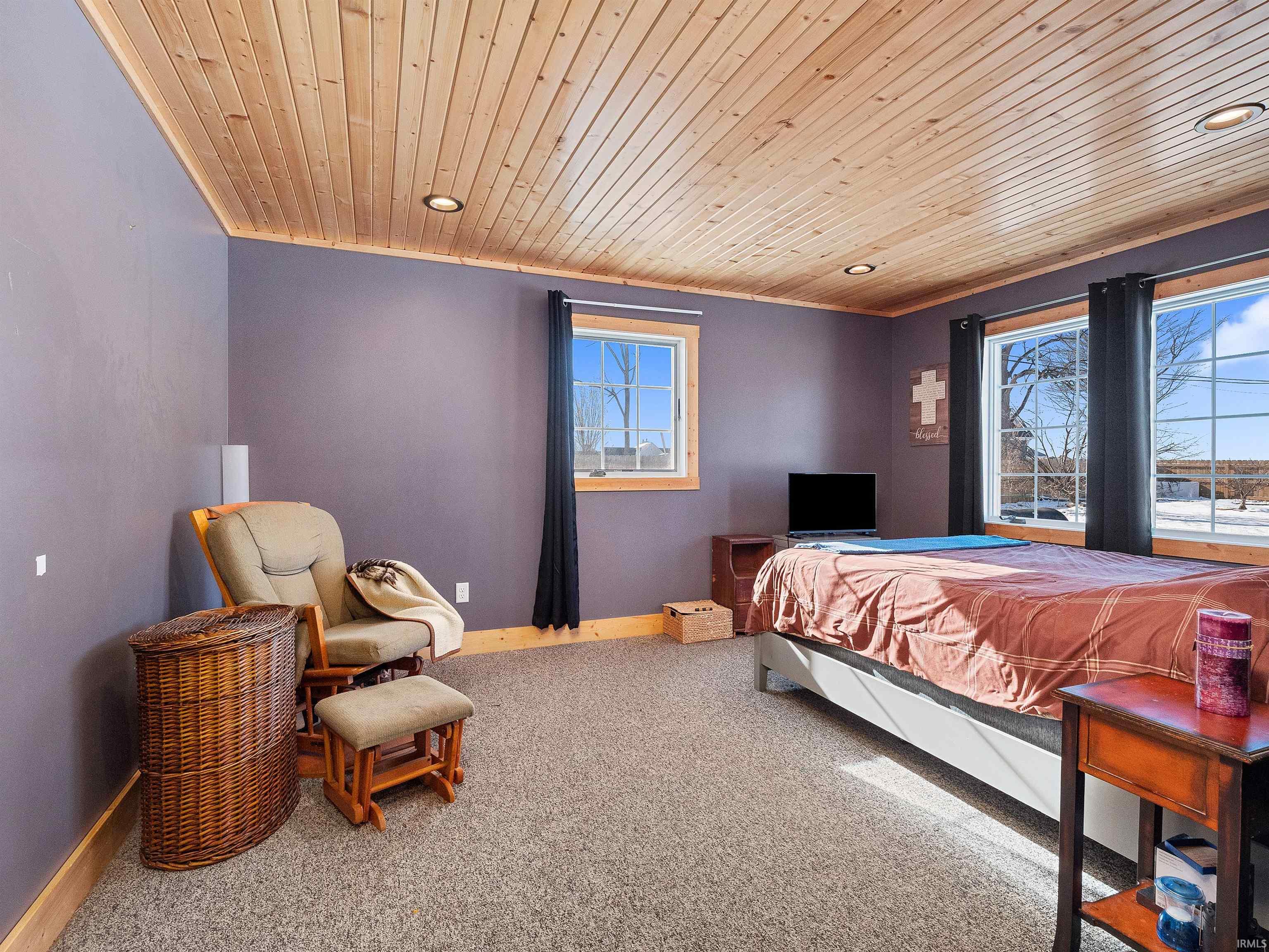 Carpeted bedroom featuring wood ceiling, multiple windows, and recessed lighting