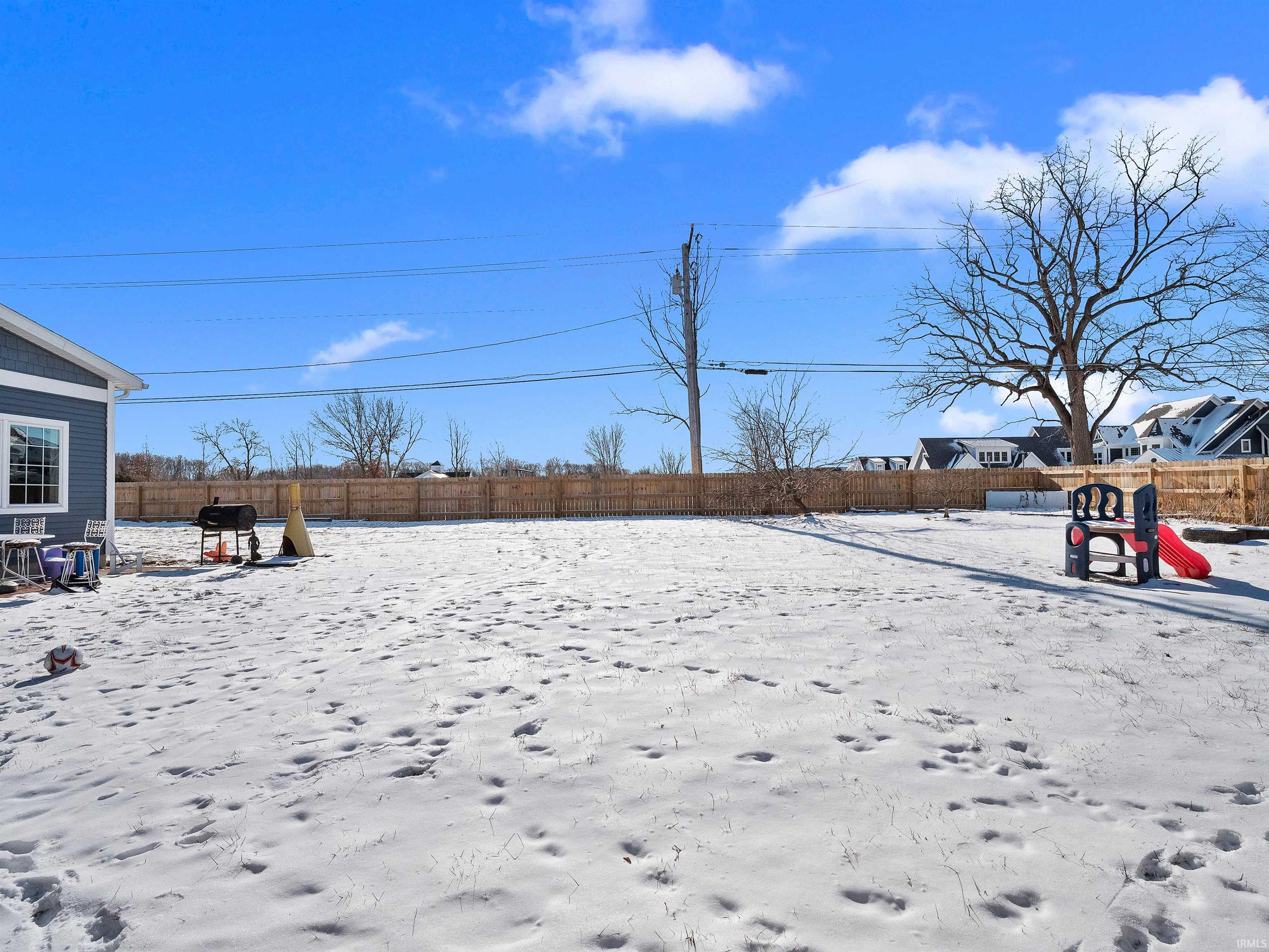 Snowy yard with a fenced backyard