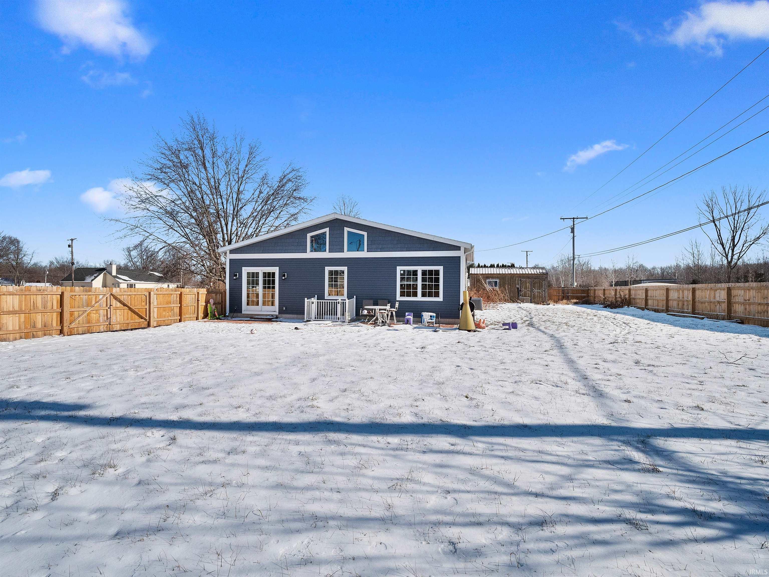 Snow covered house with a fenced backyard and a patio
