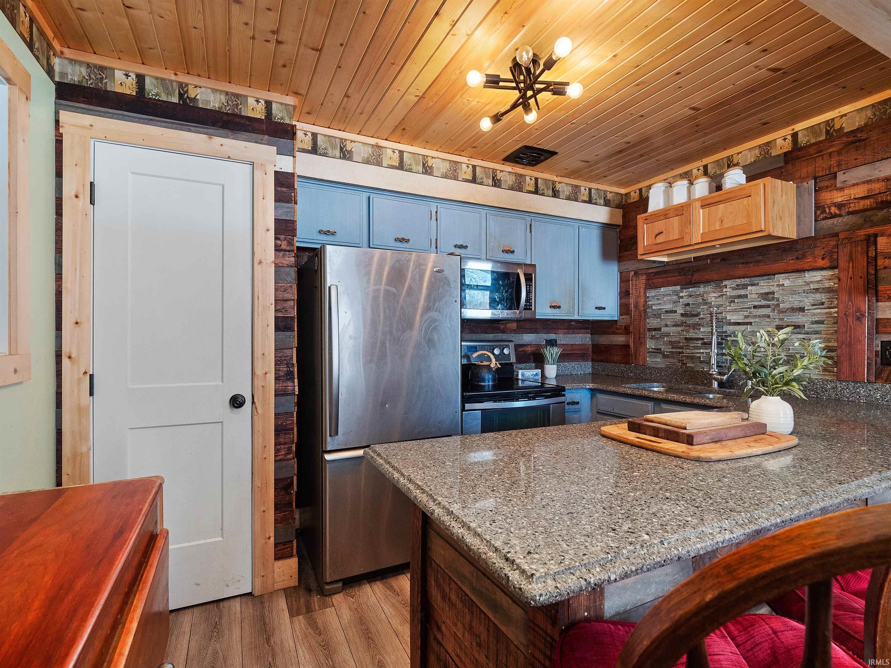 Kitchen featuring appliances with stainless steel finishes, wood ceiling, light wood finished floors, a breakfast bar area, and a peninsula
