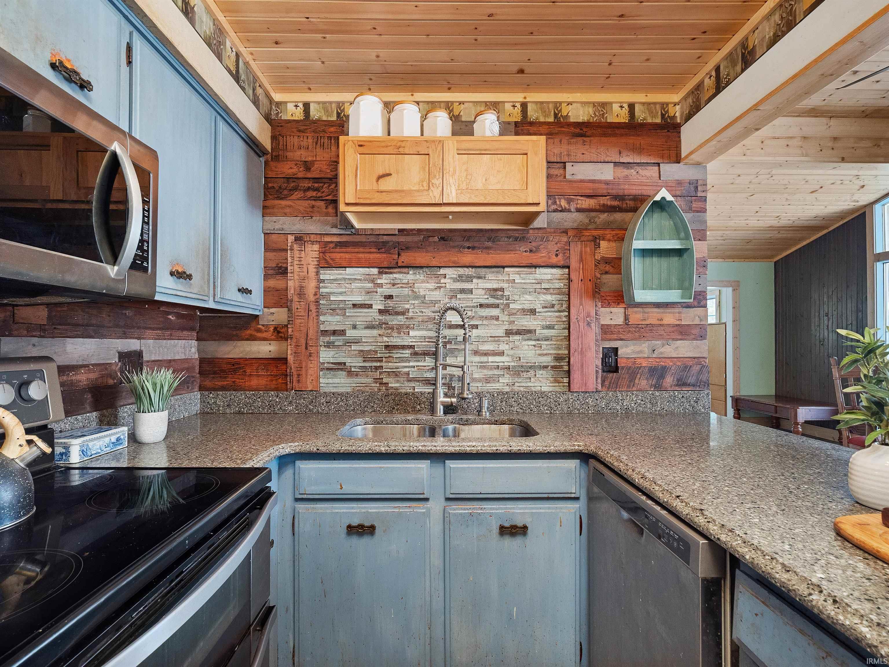 Kitchen featuring stainless steel appliances, wood ceiling, wood walls, light stone countertops, and gray cabinetry