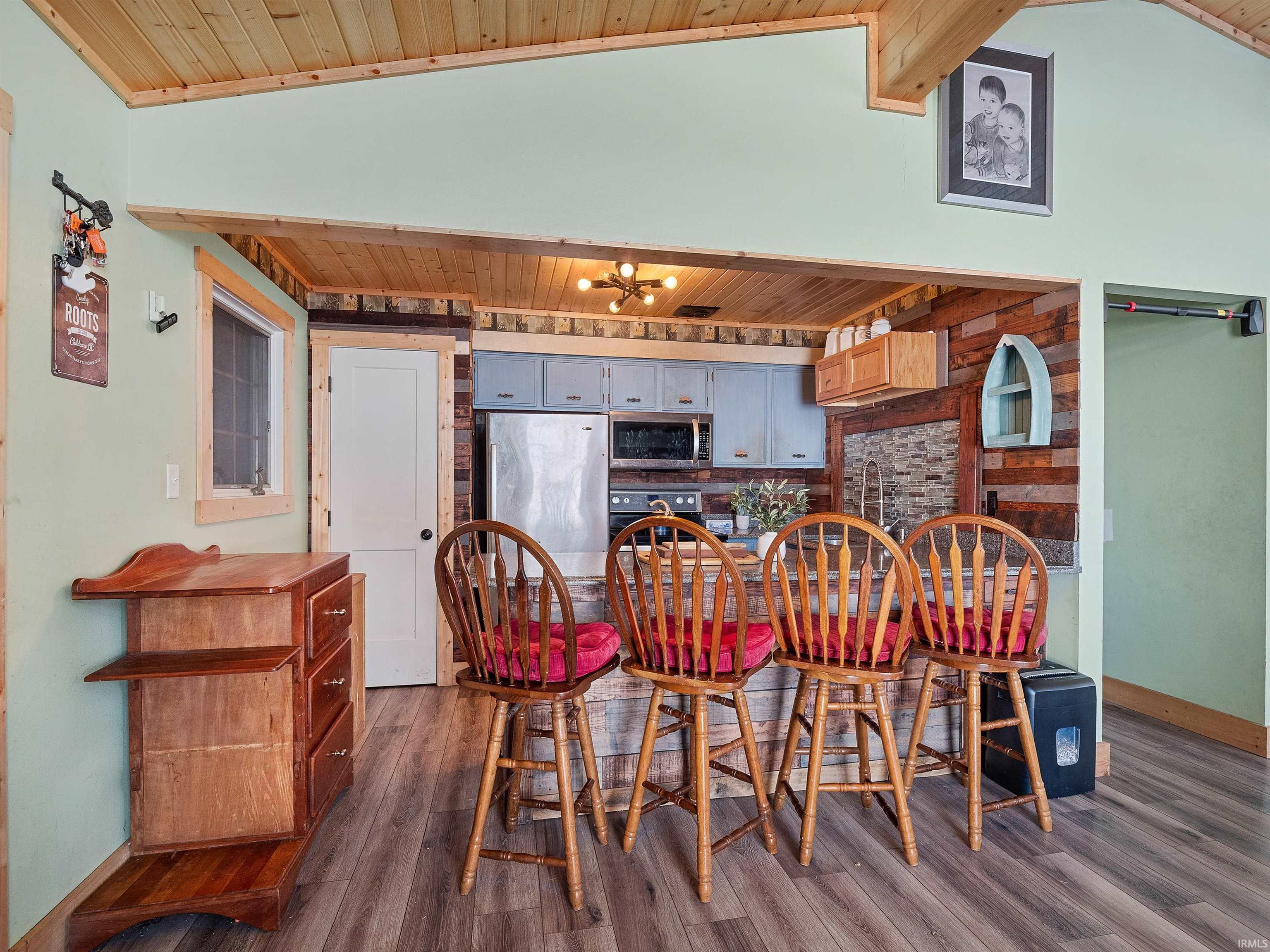 Kitchen with wood ceiling, stainless steel microwave, dark wood-type flooring, gray cabinetry, and decorative backsplash