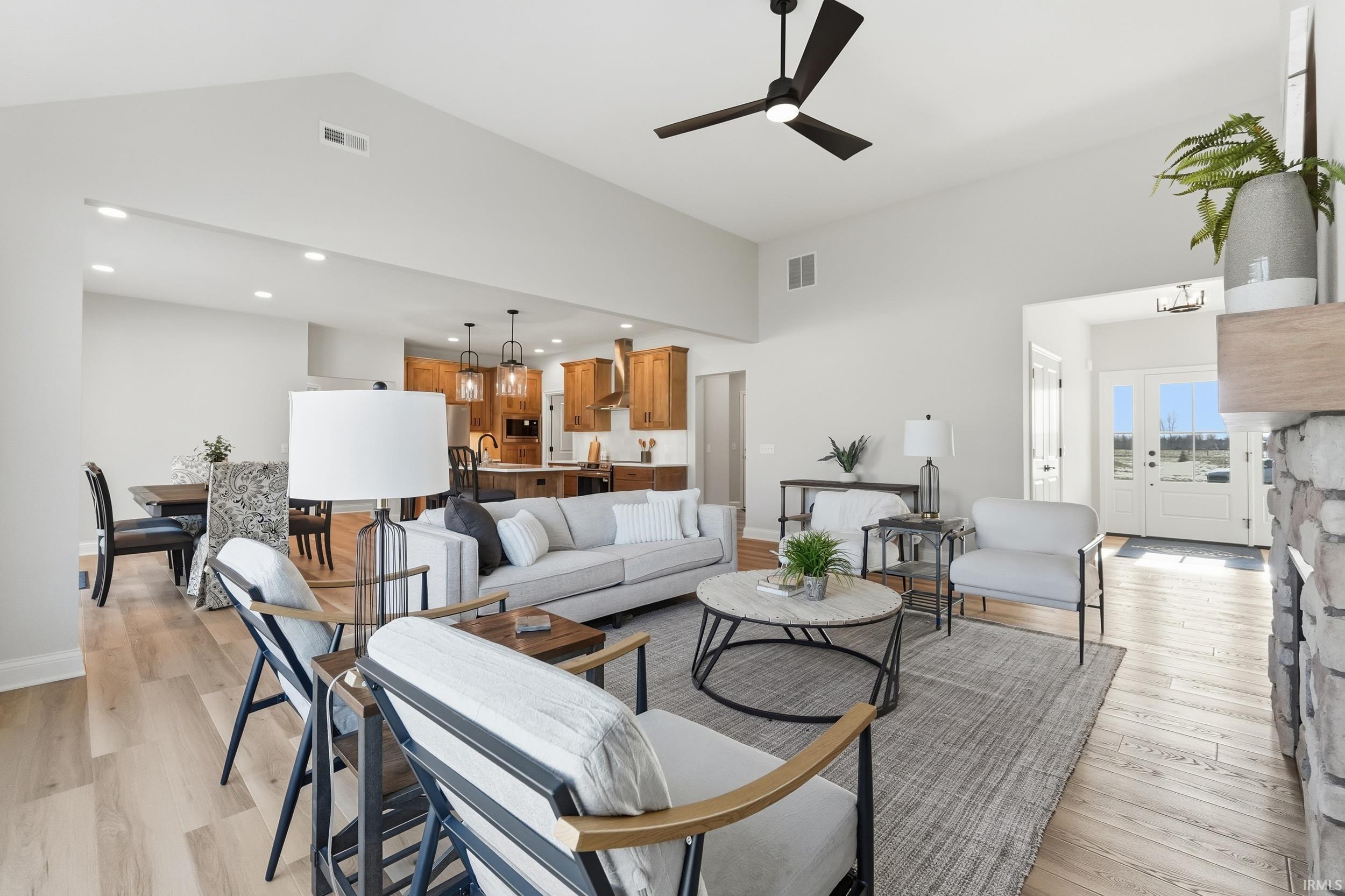 Living room featuring light wood-type flooring, ceiling fan, recessed lighting, and high vaulted ceiling