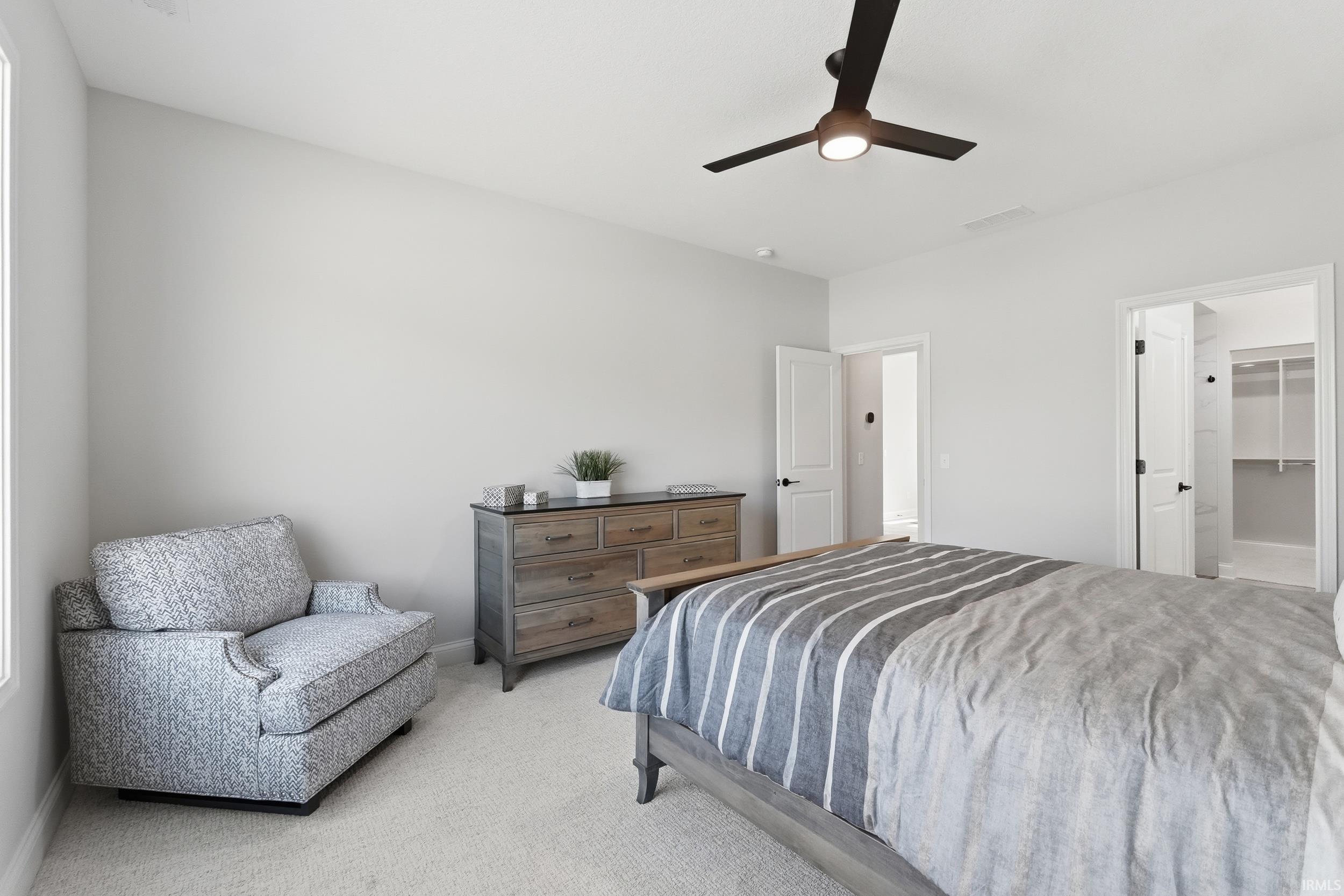 Carpeted bedroom with a ceiling fan and a walk in closet