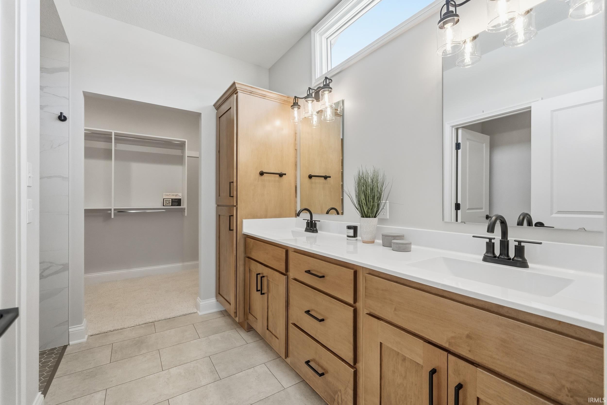 Bathroom featuring double vanity, a spacious closet, and light tile patterned floors