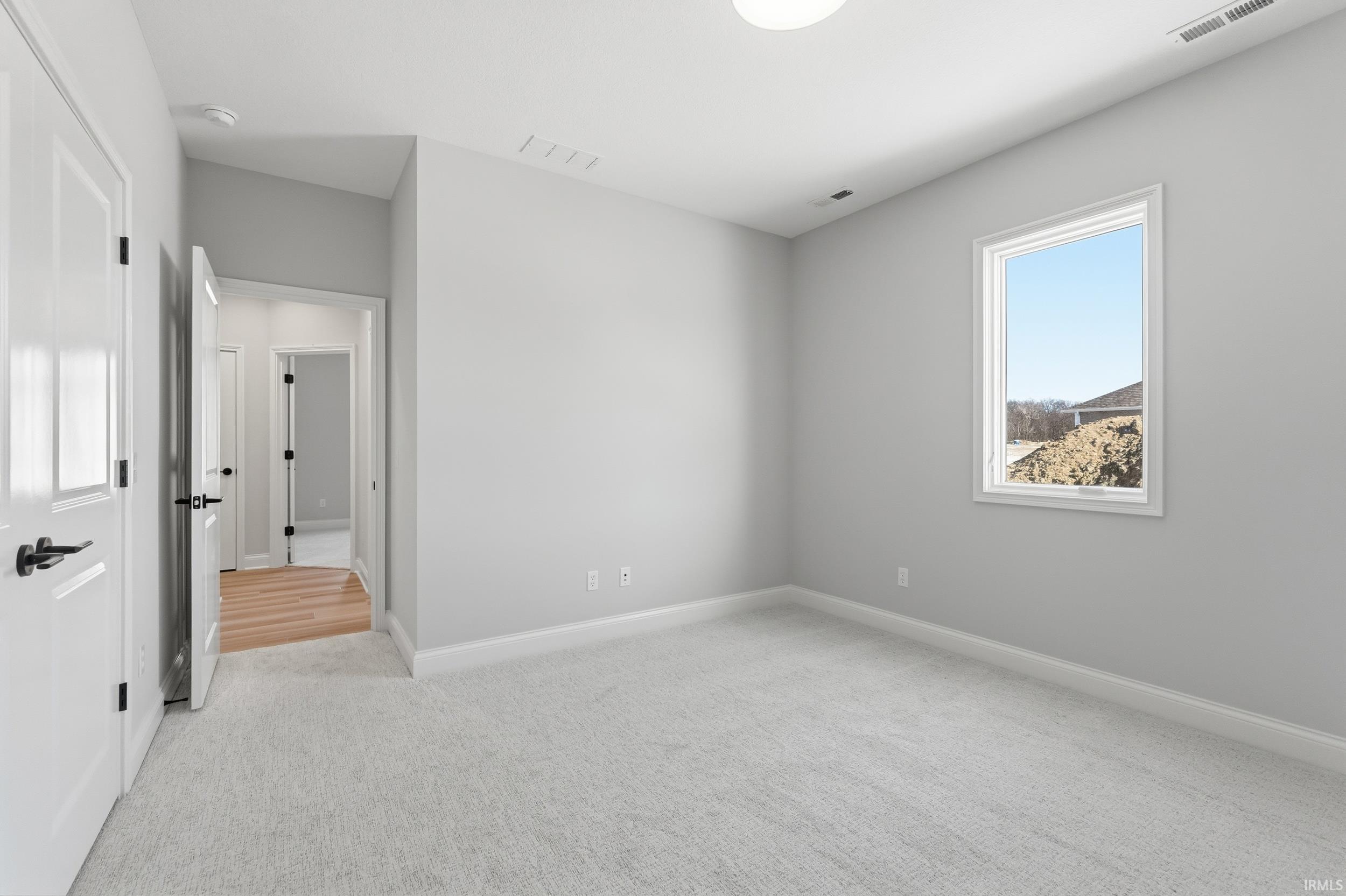 Unfurnished bedroom featuring light colored carpet and baseboards