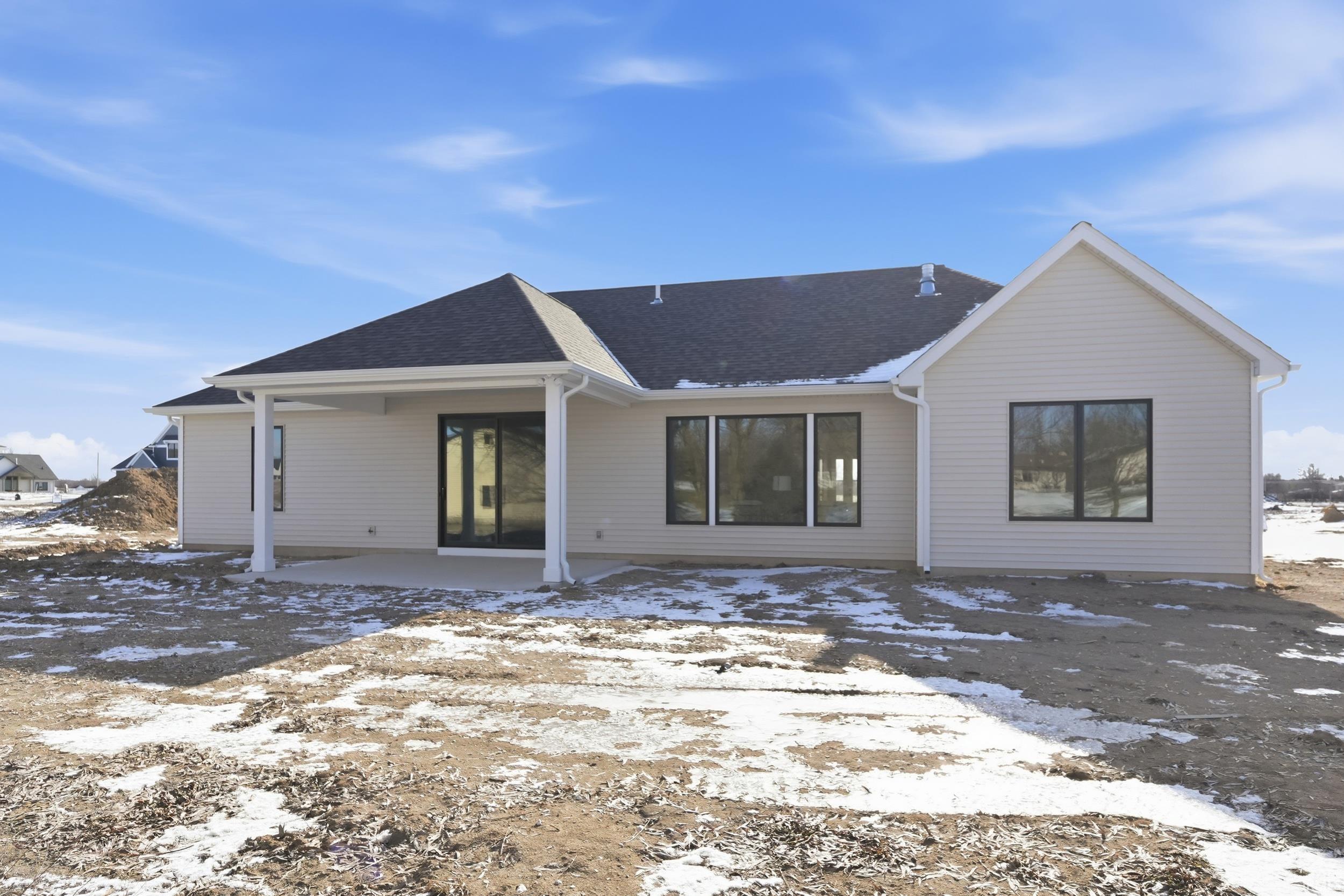 Snow covered back of property with a patio and roof with shingles