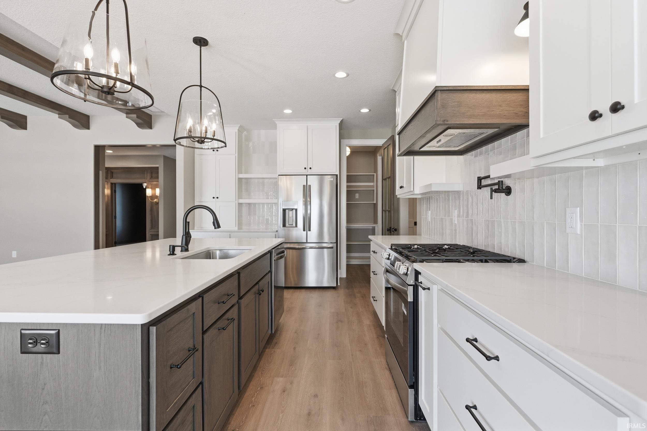 Kitchen featuring stainless steel appliances, white cabinets, tiled backsplash, and custom exhaust hood