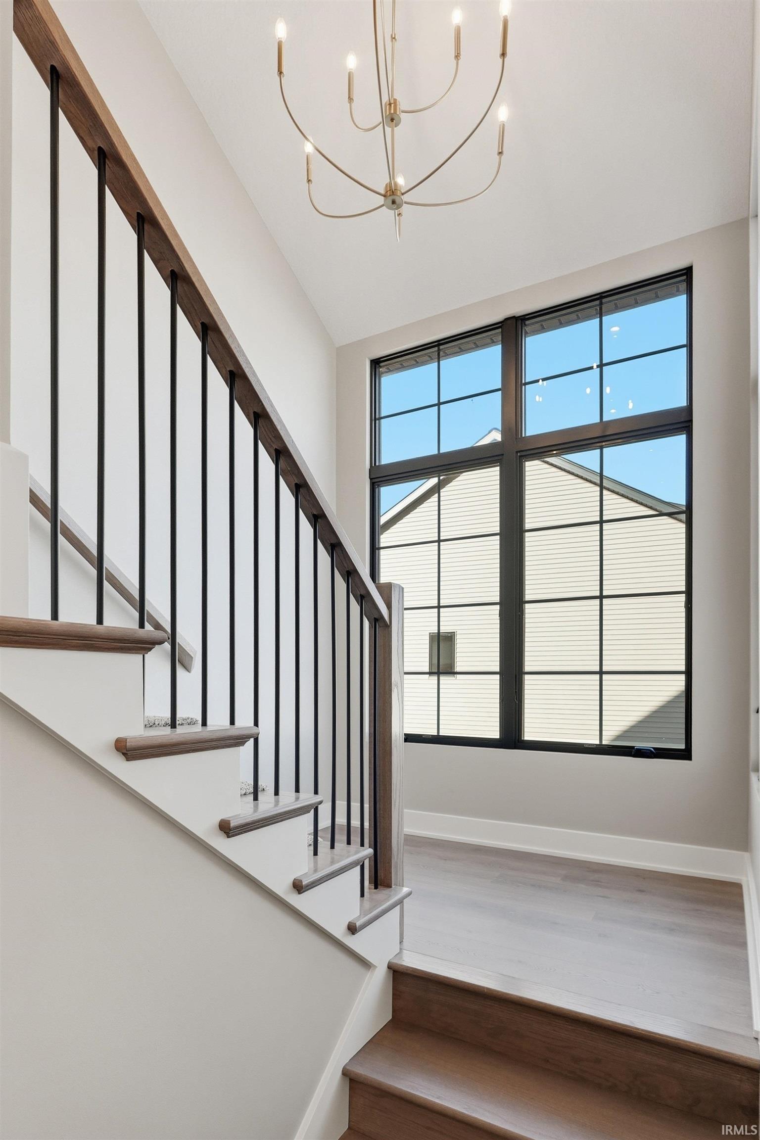 Stairway with wood finished floors and a chandelier