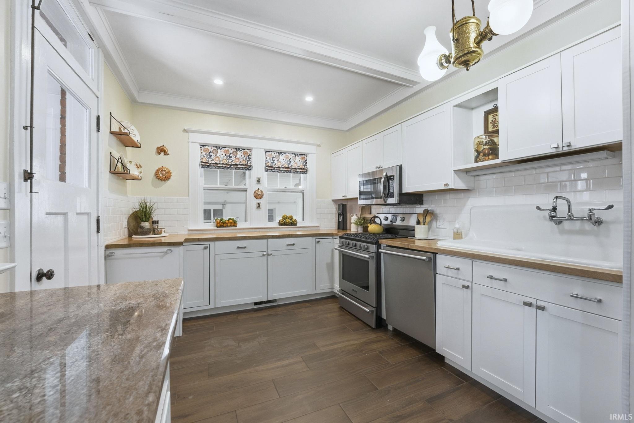 Kitchen with open shelves, white cabinetry, stainless steel appliances, dark wood finished floors, and crown molding