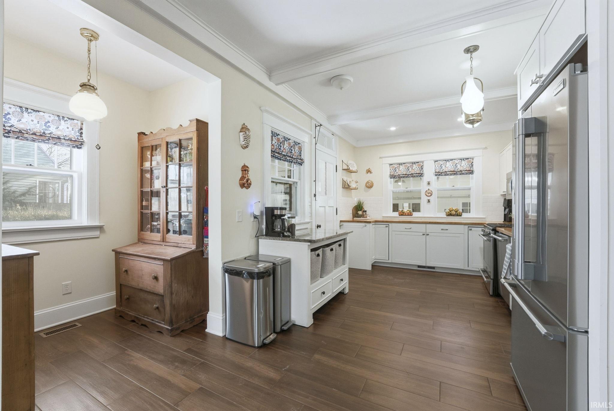 Kitchen featuring hanging light fixtures, white cabinets, appliances with stainless steel finishes, dark wood-style floors, and wooden counters