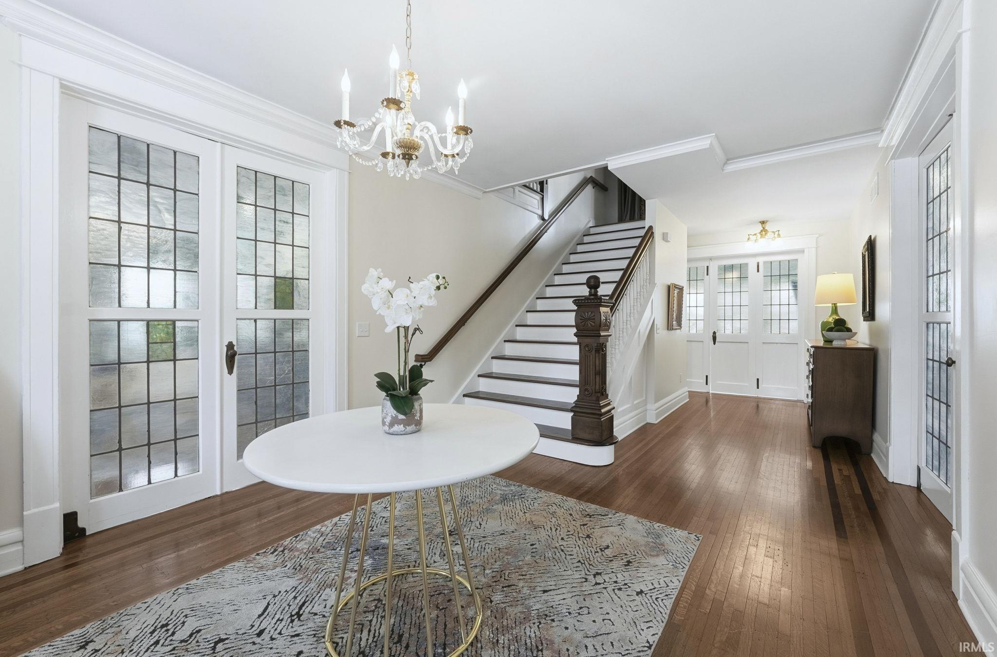 Foyer with french doors, dark wood-style flooring, crown molding, and a chandelier