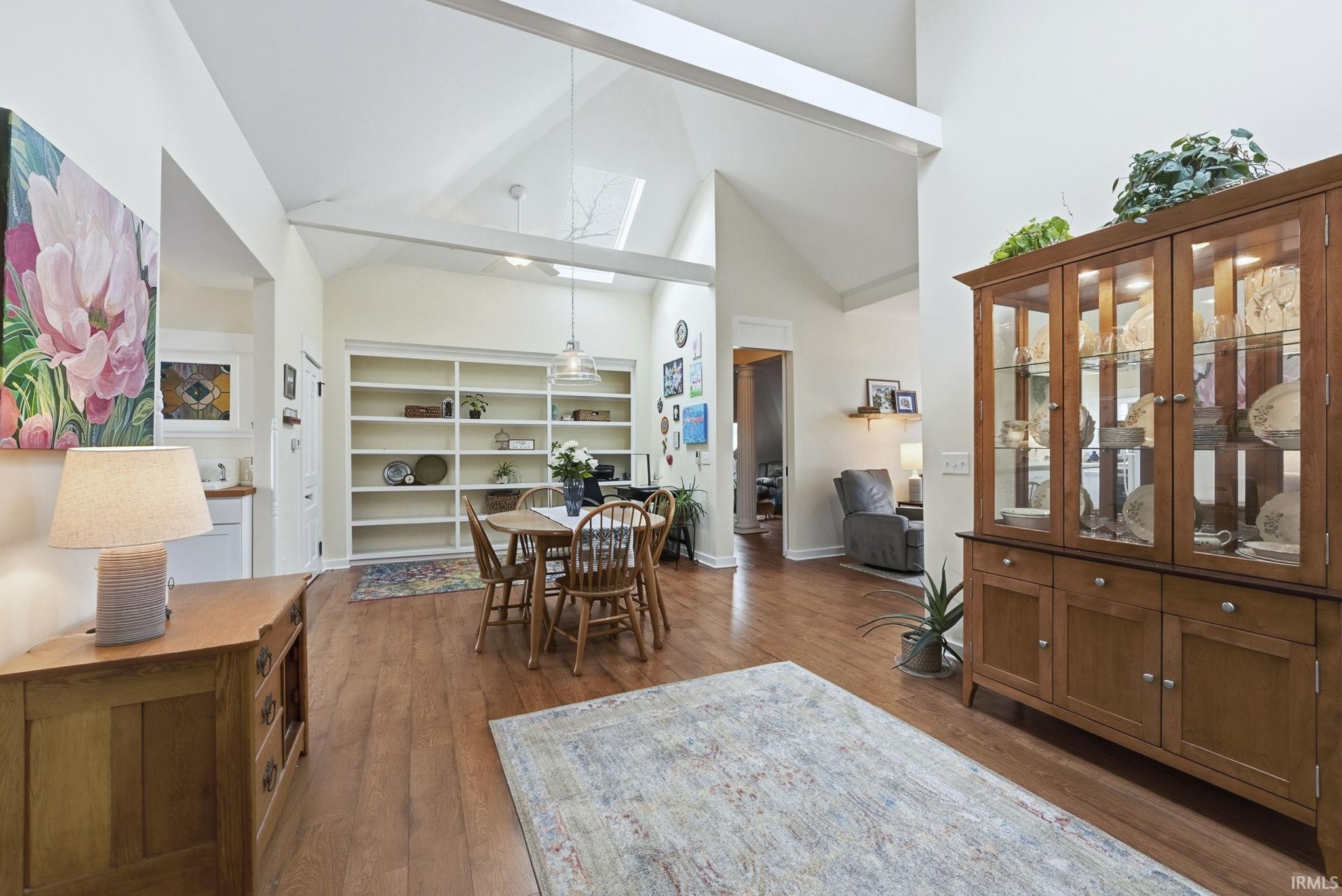 Dining room with high vaulted ceiling, dark wood-type flooring, and a skylight