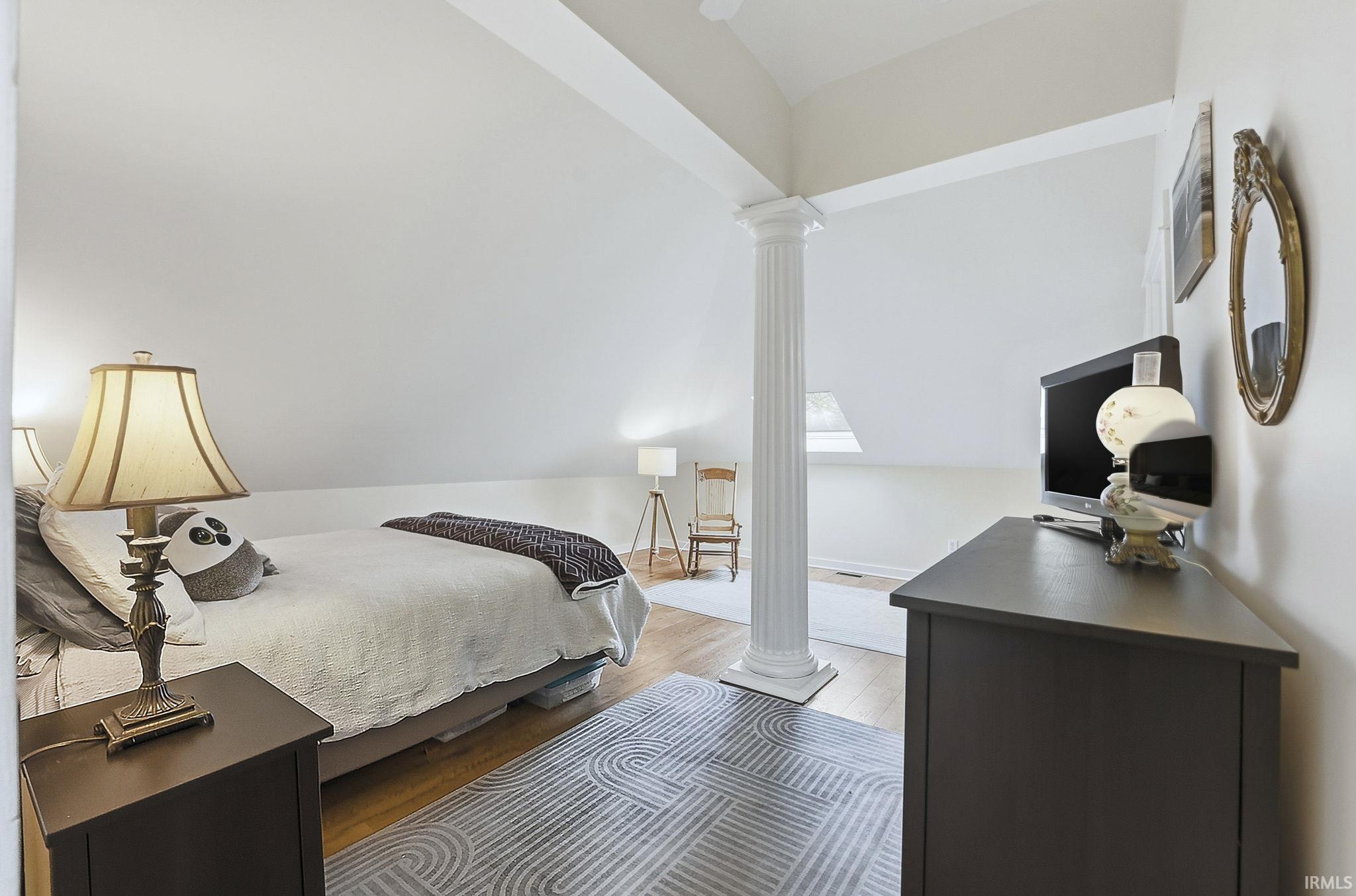 Bedroom 1 in upstairs apartment.with decorative columns and wood finished floors