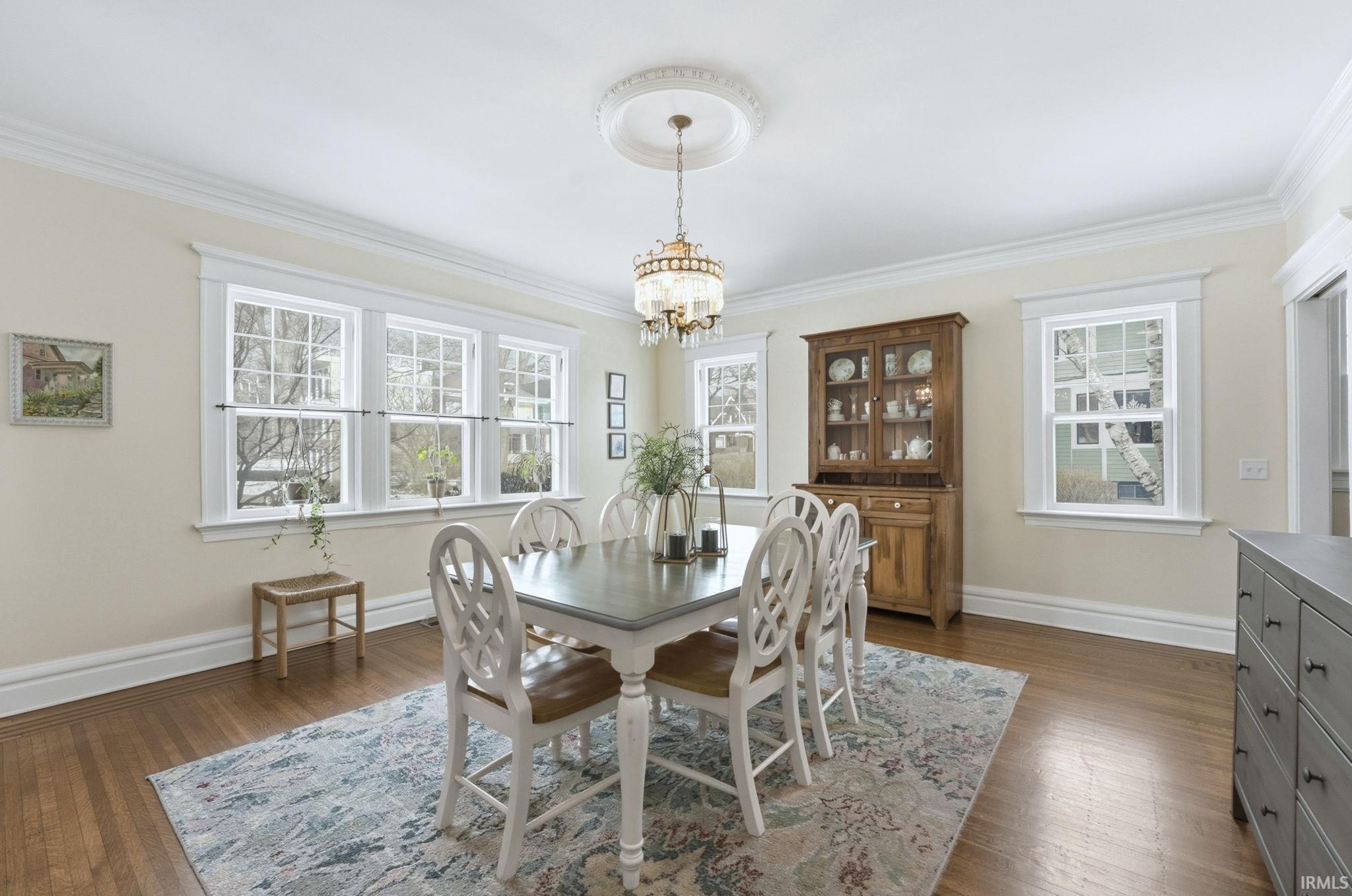 Dining room with dark wood-style flooring, a chandelier, and crown molding