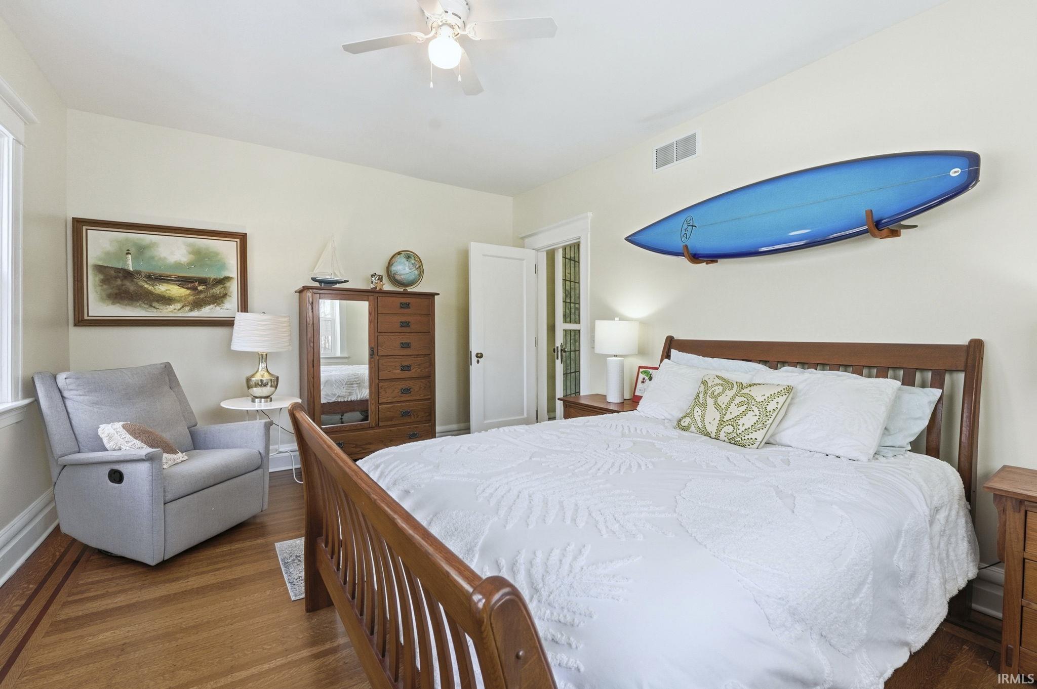 Bedroom on main level with dark wood-type flooring and ceiling fan