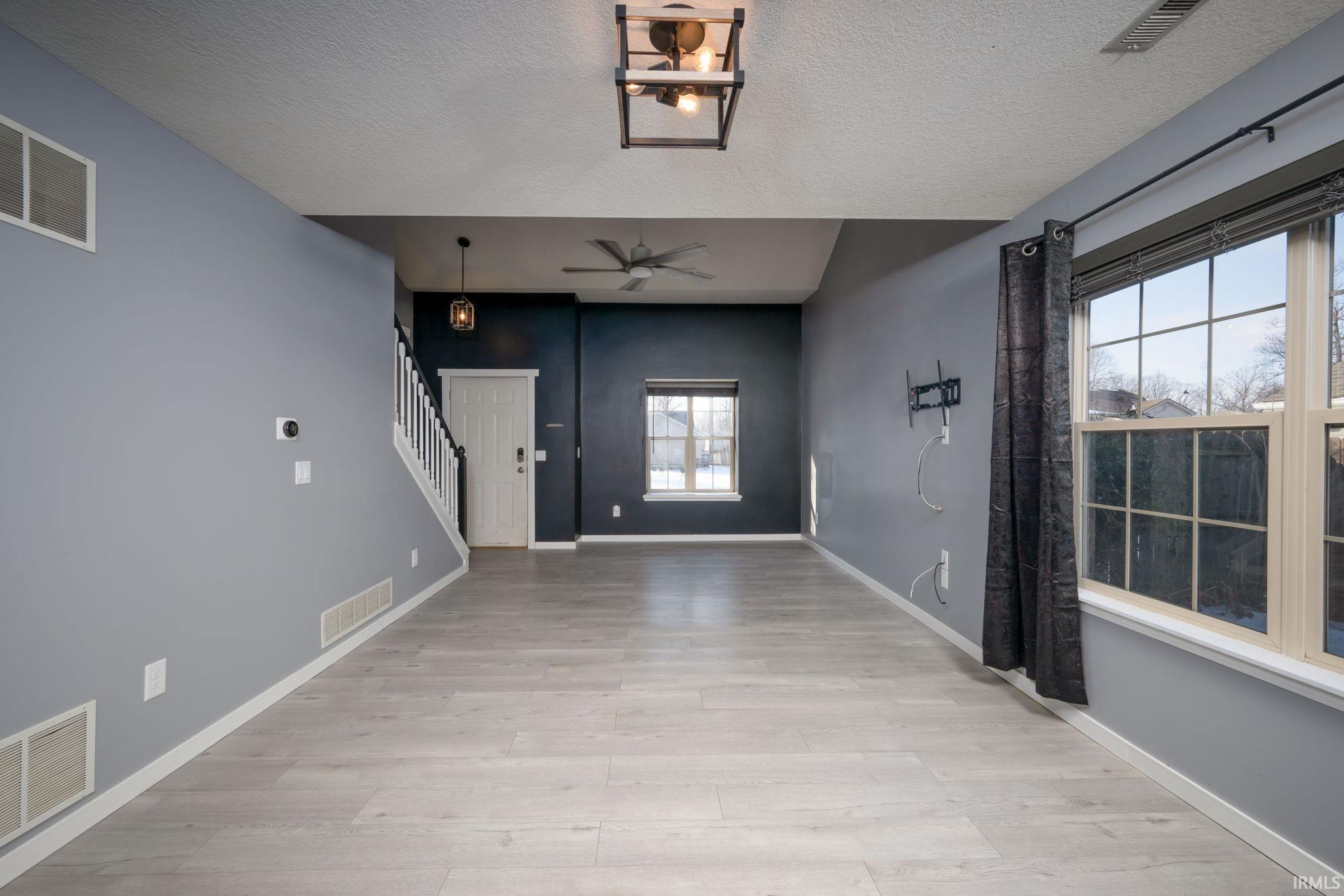 Foyer entrance featuring a ceiling fan, light wood-type flooring, stairs, and a textured ceiling