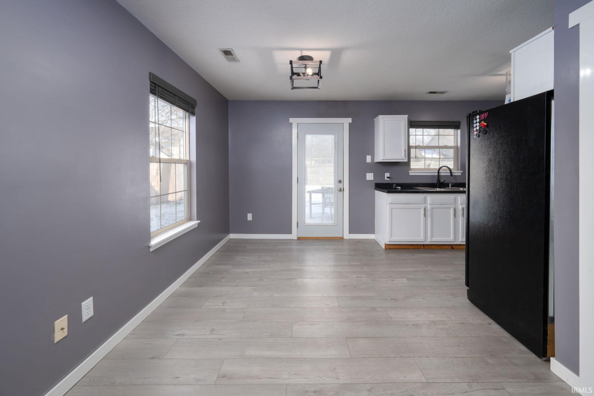 Kitchen featuring dark countertops, freestanding refrigerator, white cabinetry, and light wood finished floors