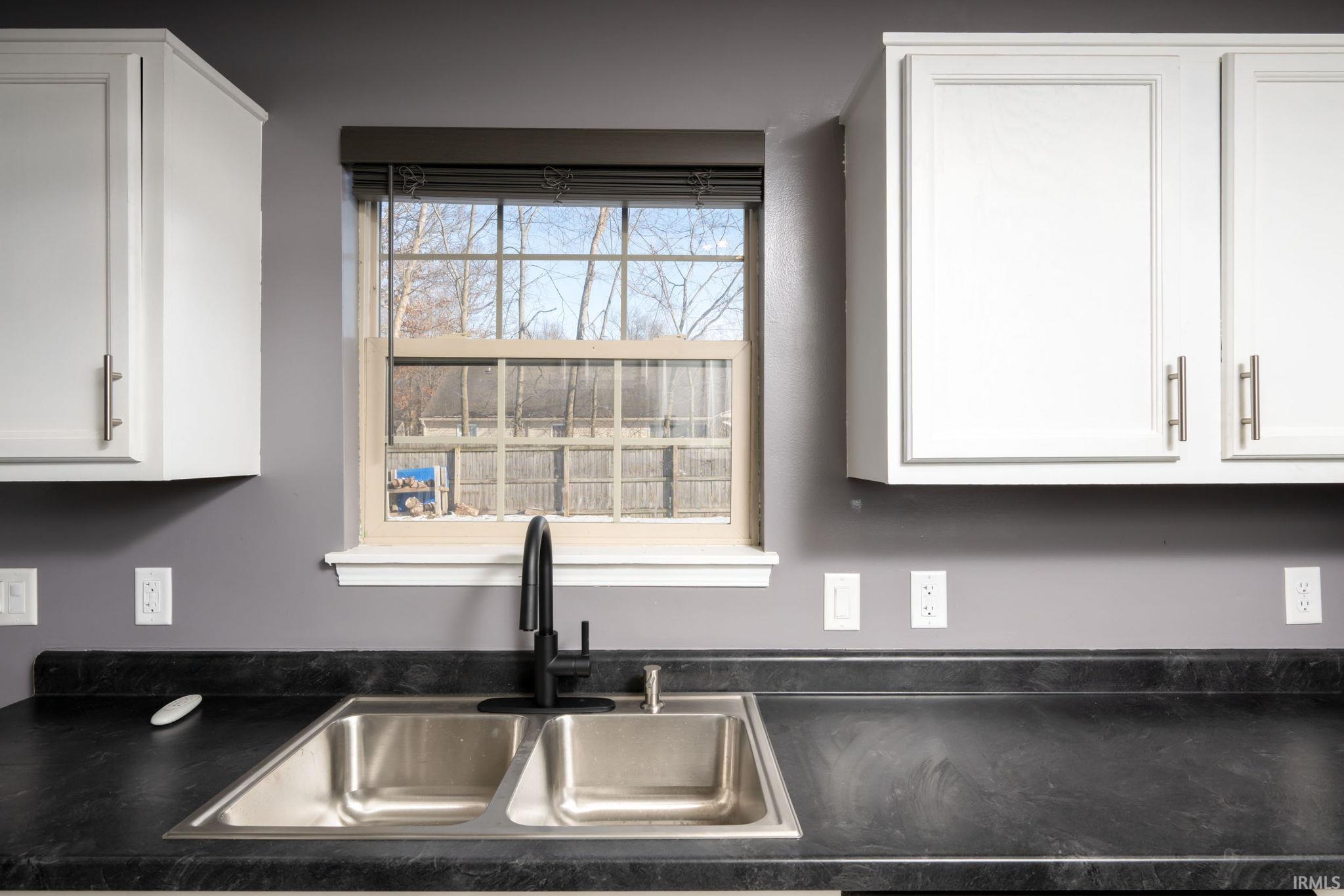 Kitchen featuring white cabinets and dark countertops