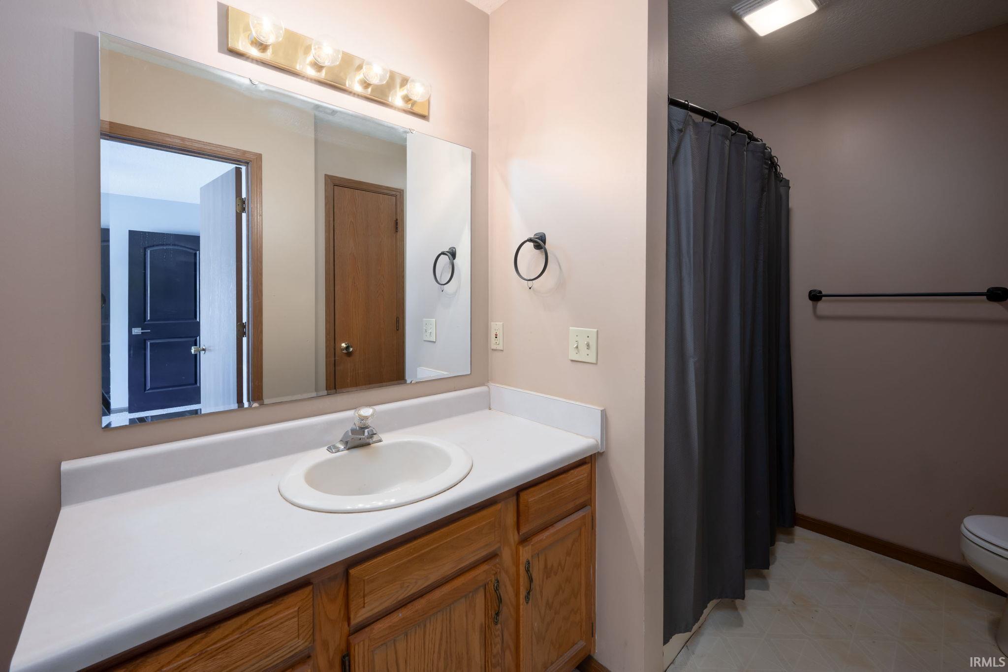 Full bath with a shower with shower curtain, vanity, and light floors
