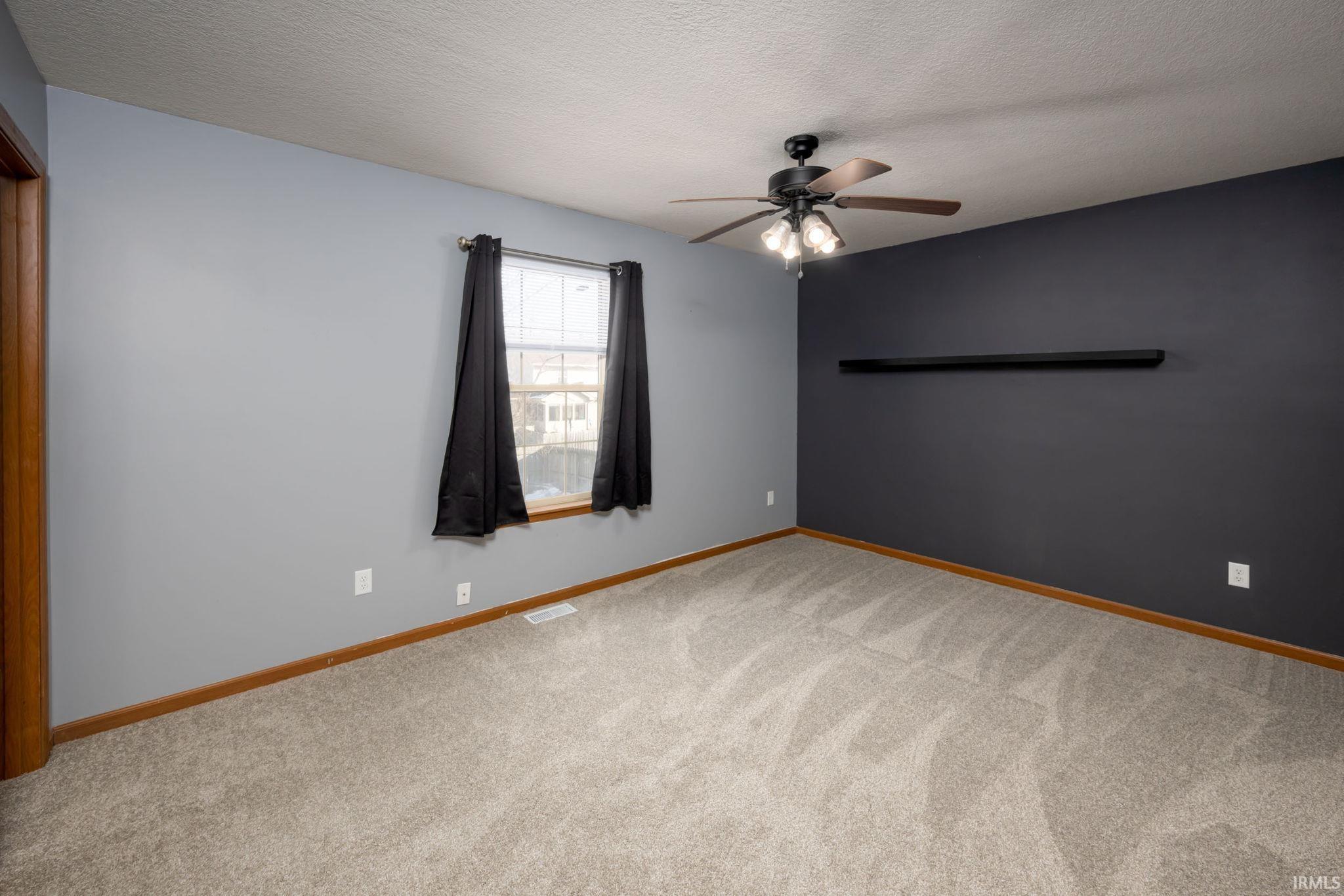Carpeted spare room featuring a textured ceiling and ceiling fan