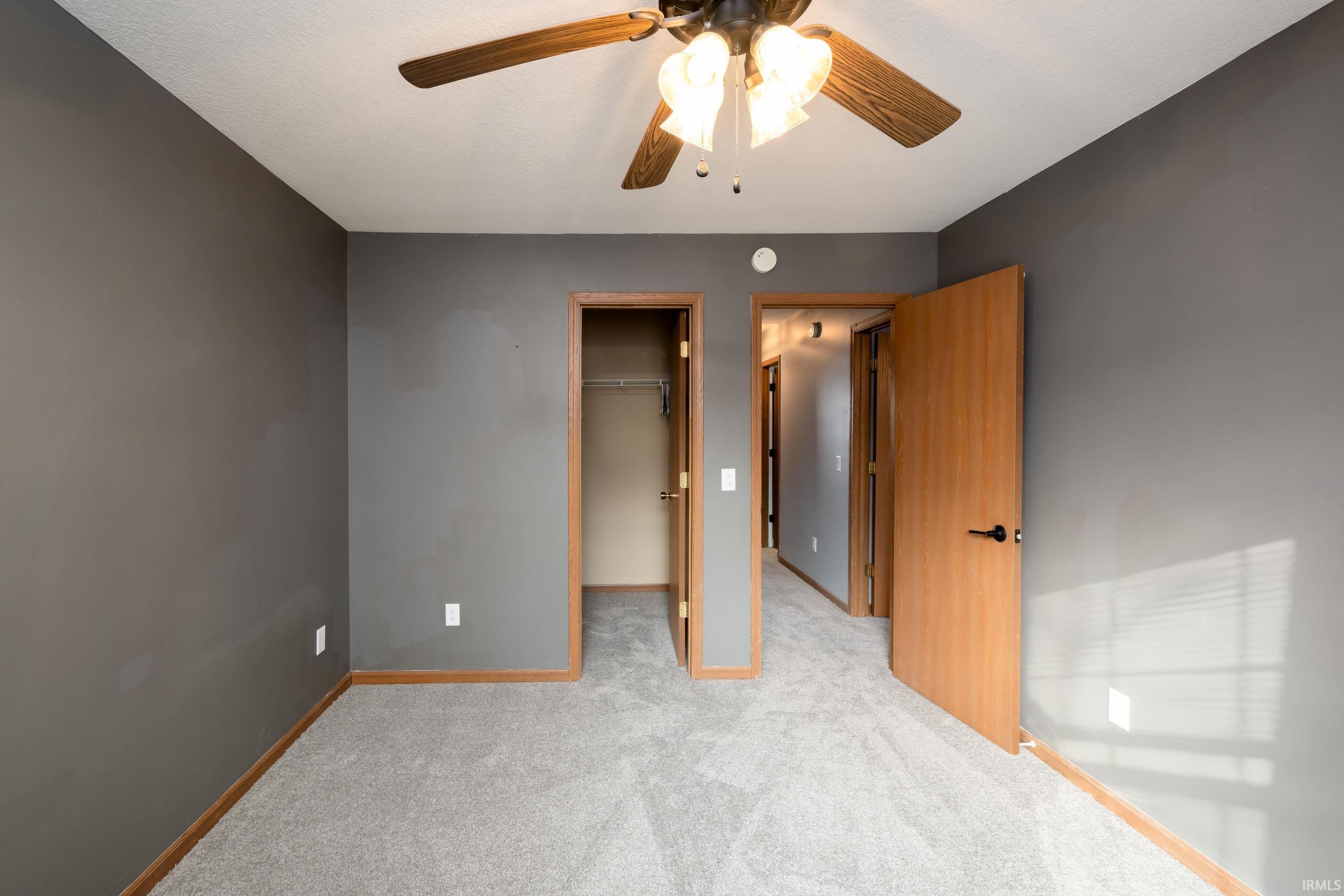 Unfurnished bedroom with a walk in closet, ceiling fan, and carpet flooring