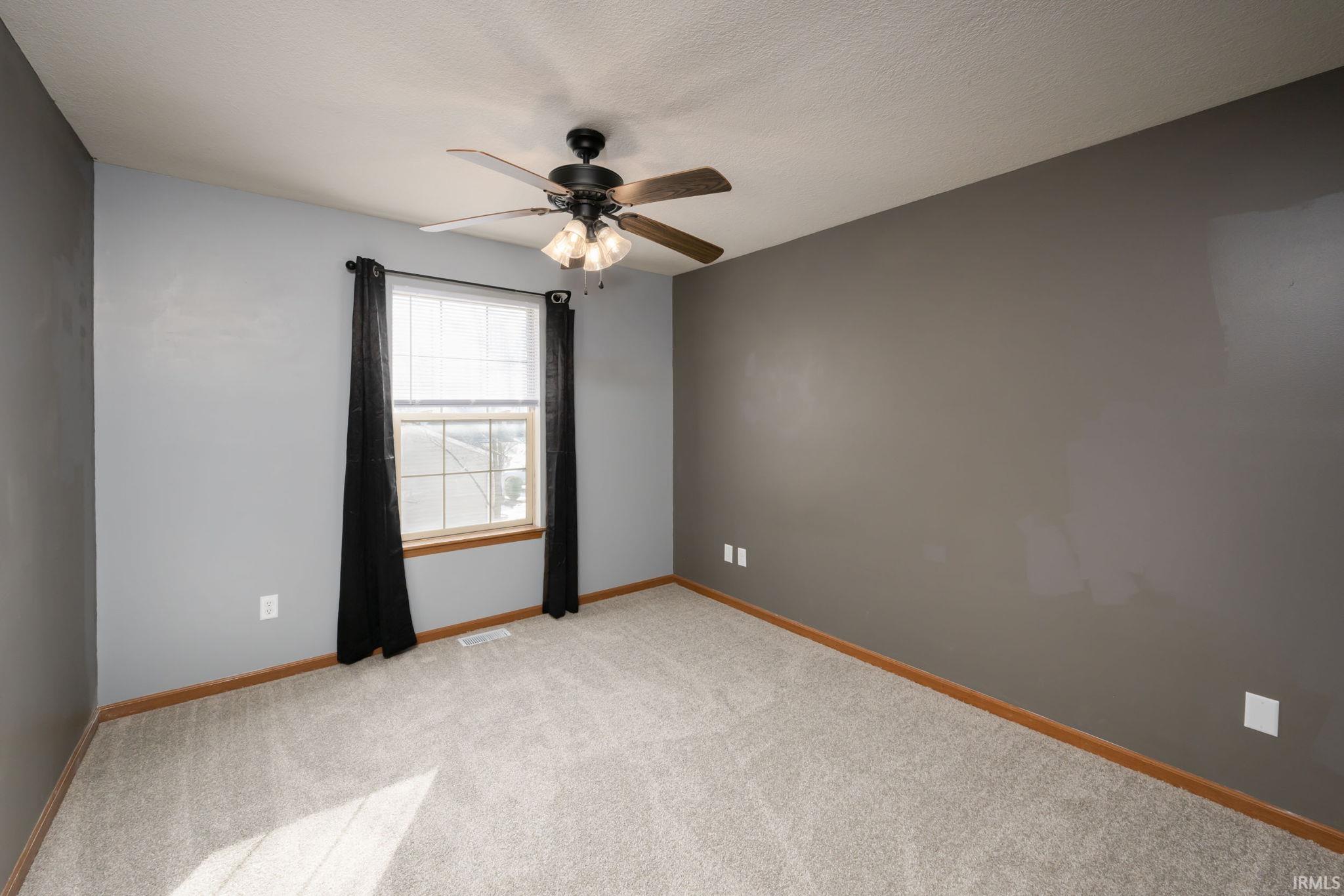 Empty room with light carpet, a ceiling fan, and a textured ceiling