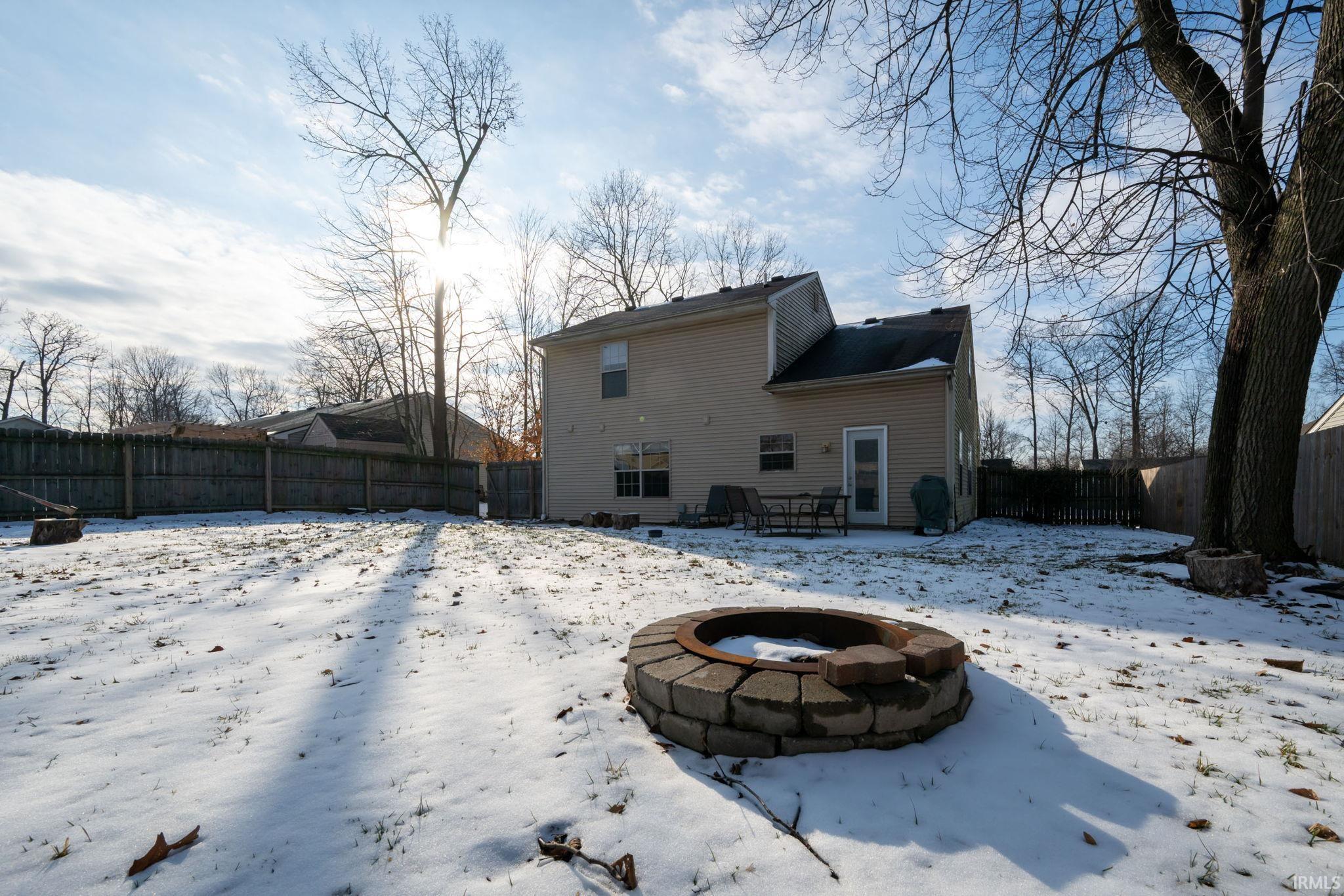 Snow covered house featuring a patio area, a fenced backyard, and an outdoor fire pit