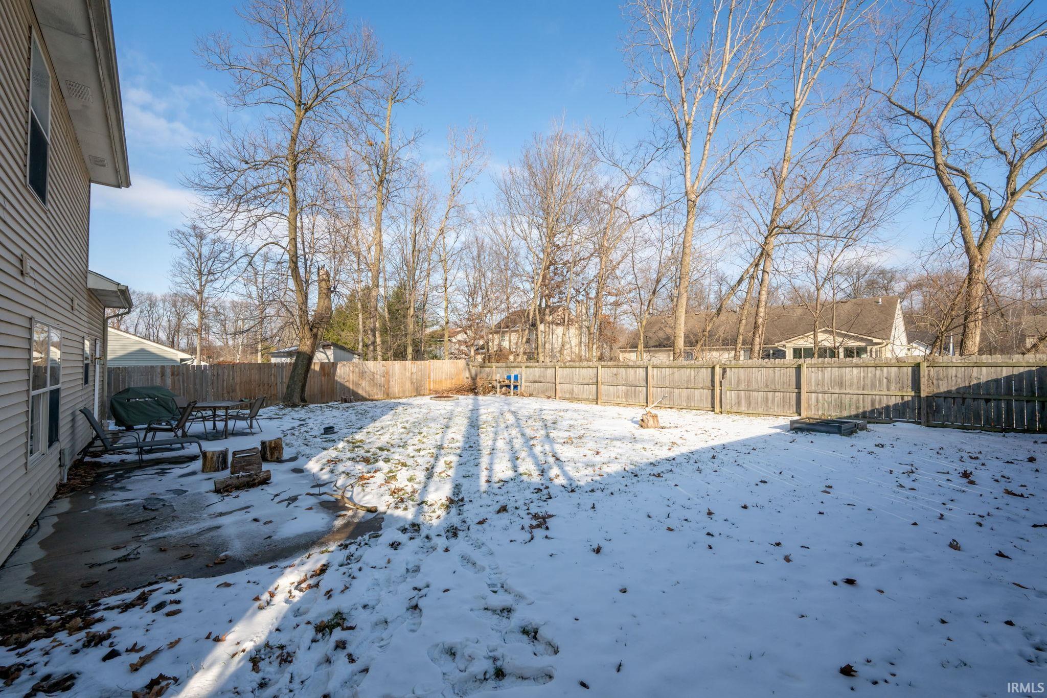 Yard layered in snow featuring a fenced backyard and a patio area