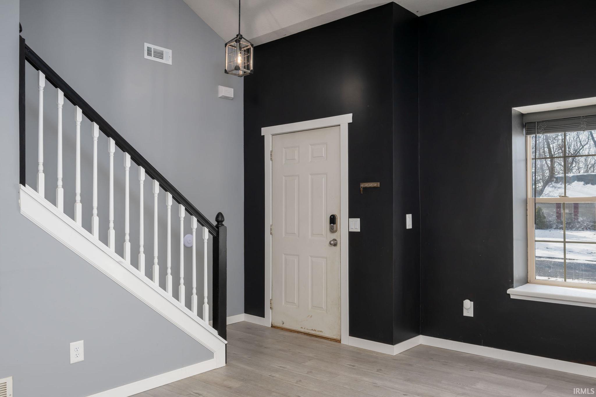 Foyer entrance featuring stairs, light wood finished floors, and a towering ceiling