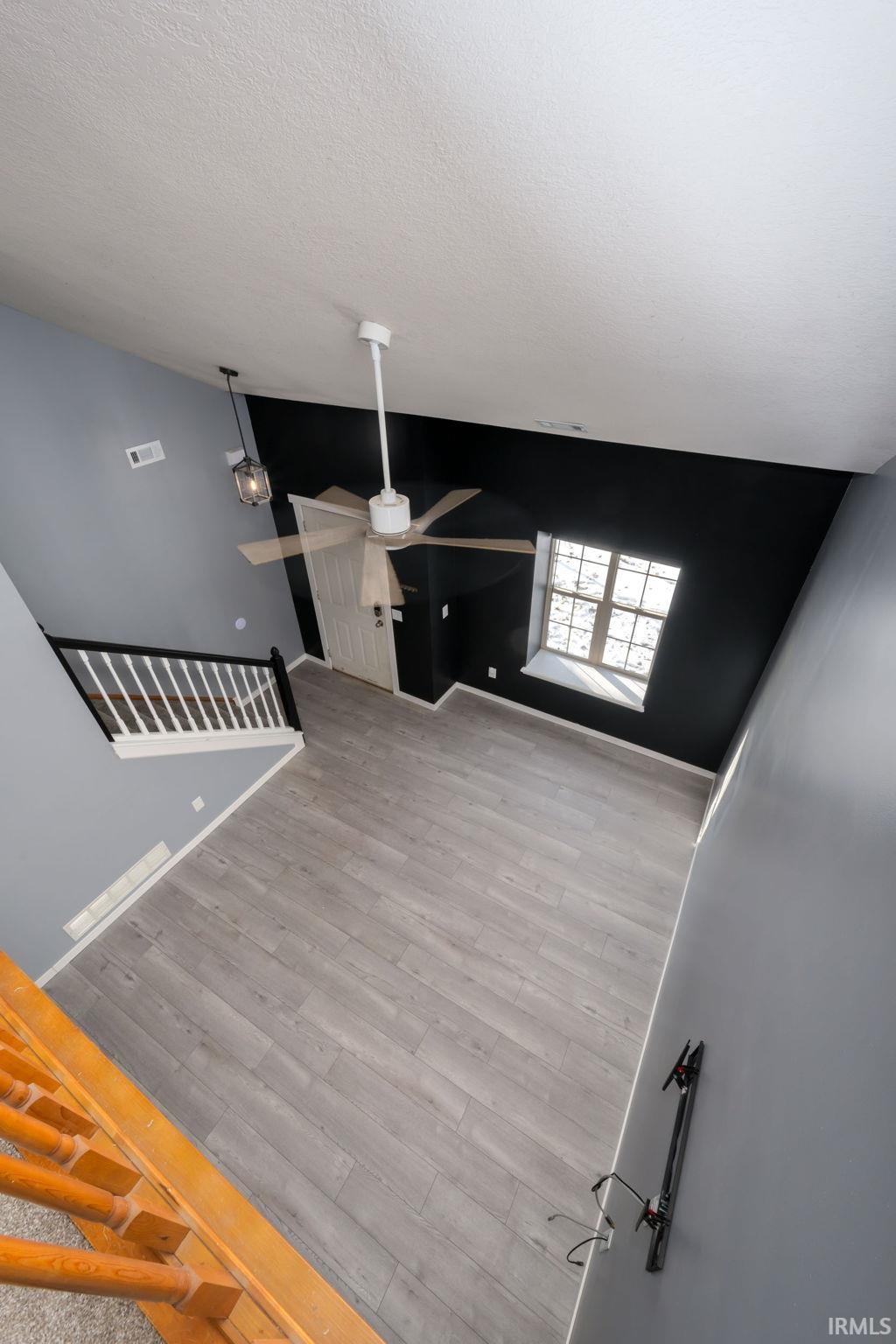 Unfurnished living room featuring ceiling fan, light wood-style floors, and a textured ceiling