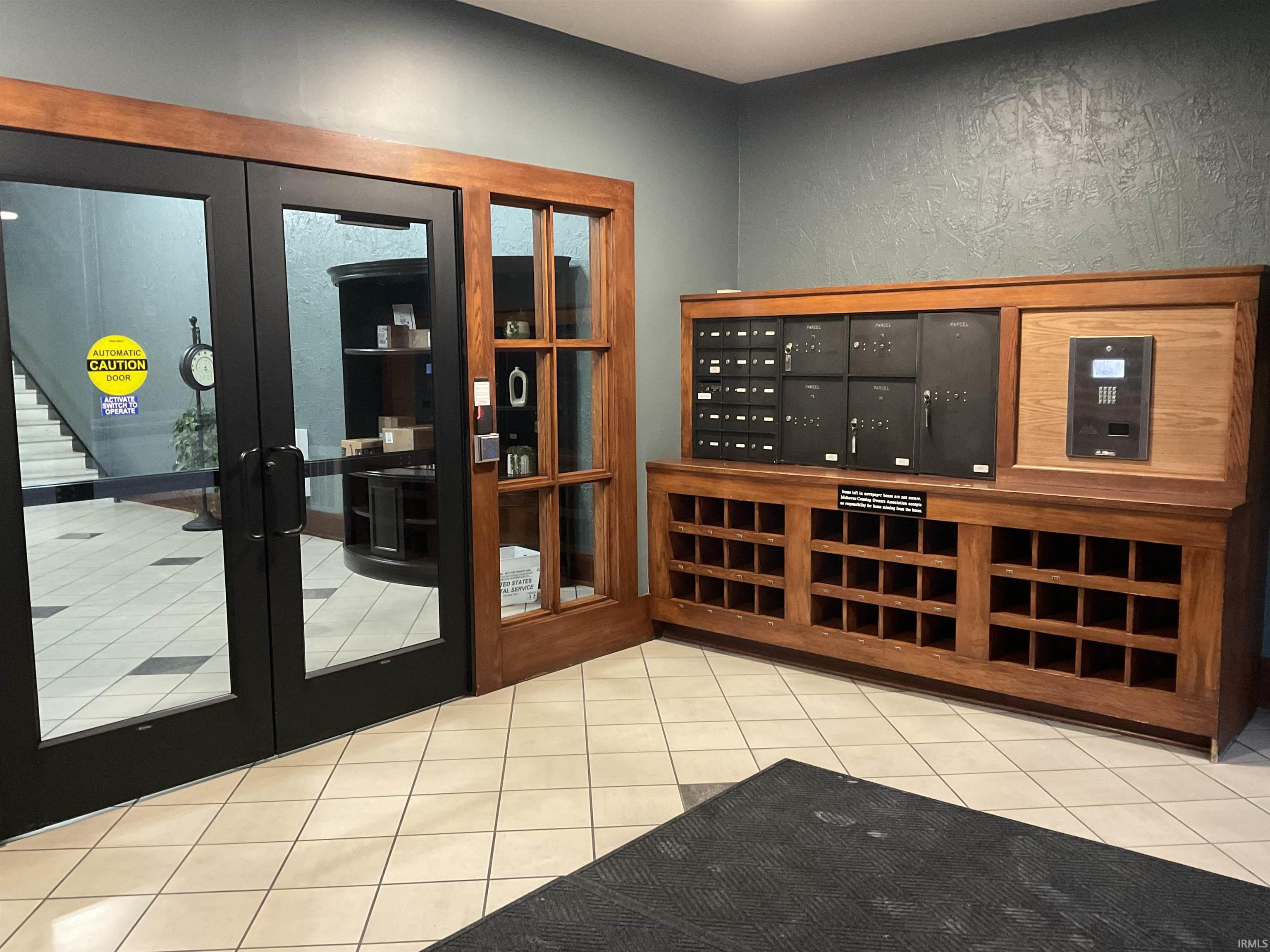 Secure entrance featuring light tile patterned flooring, french doors and mail area.
