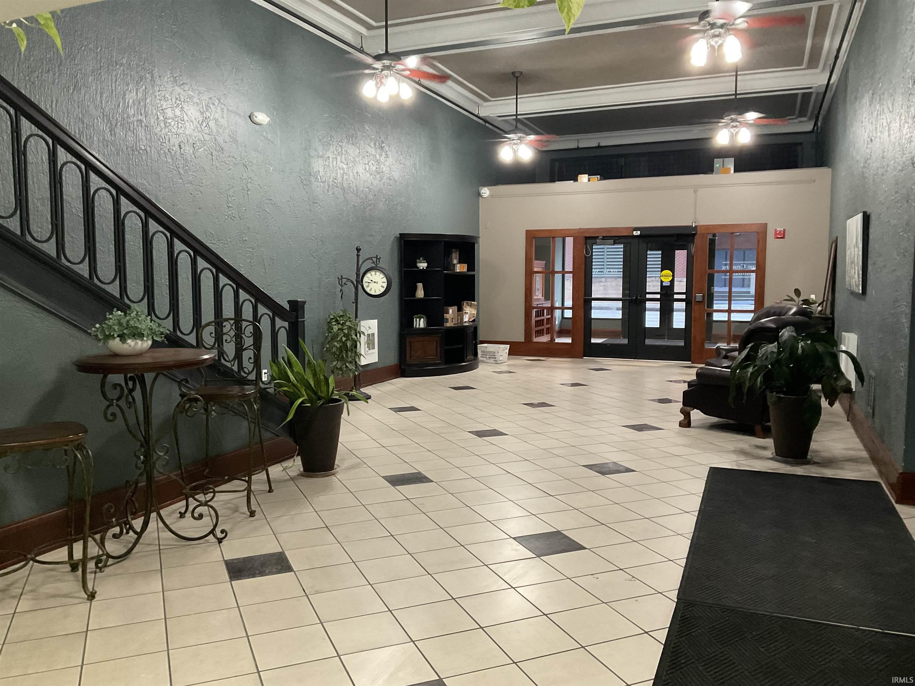 Common area with a textured wall, a towering ceiling, stairs, and crown molding