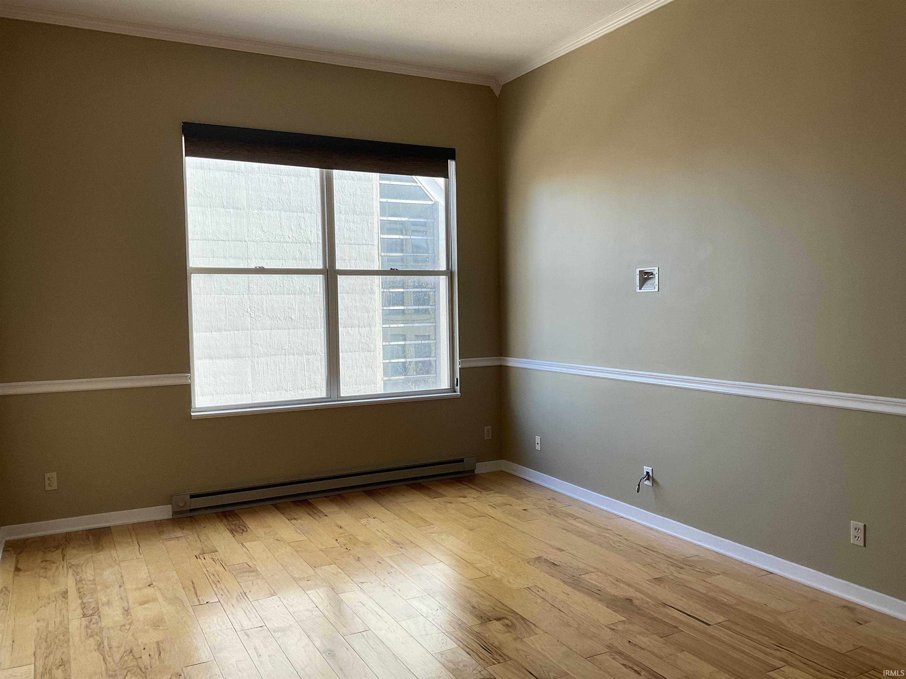 Empty room featuring light wood-style flooring, and crown molding
