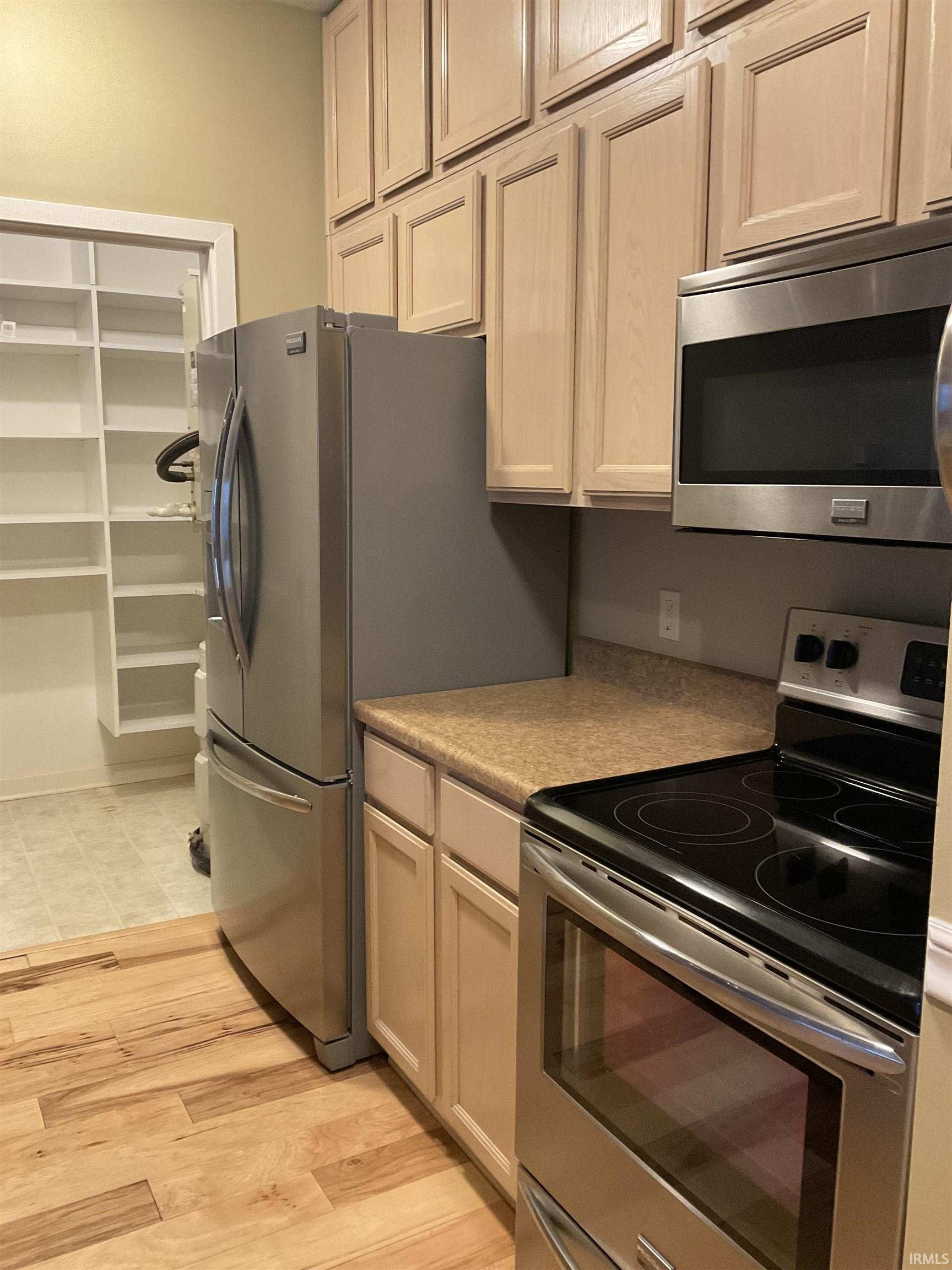 Kitchen featuring appliances with stainless steel finishes, light wood-type flooring, and light countertops