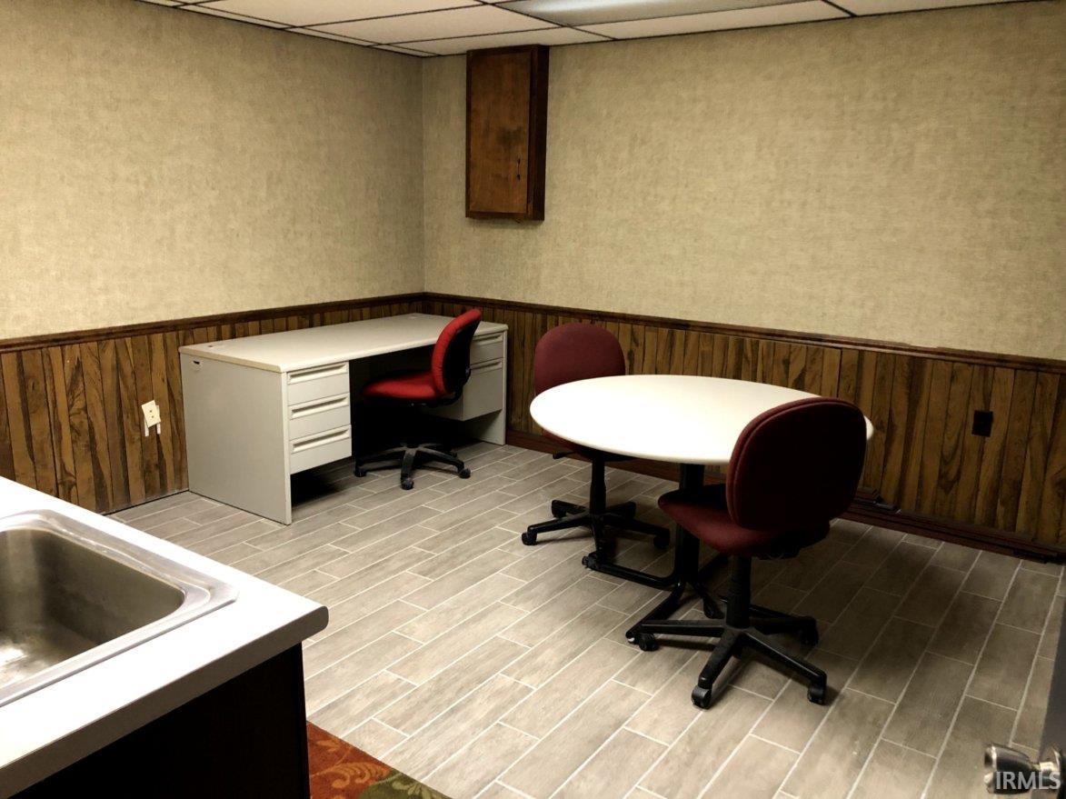 Office featuring a wainscoted wall, a paneled ceiling, and wood walls