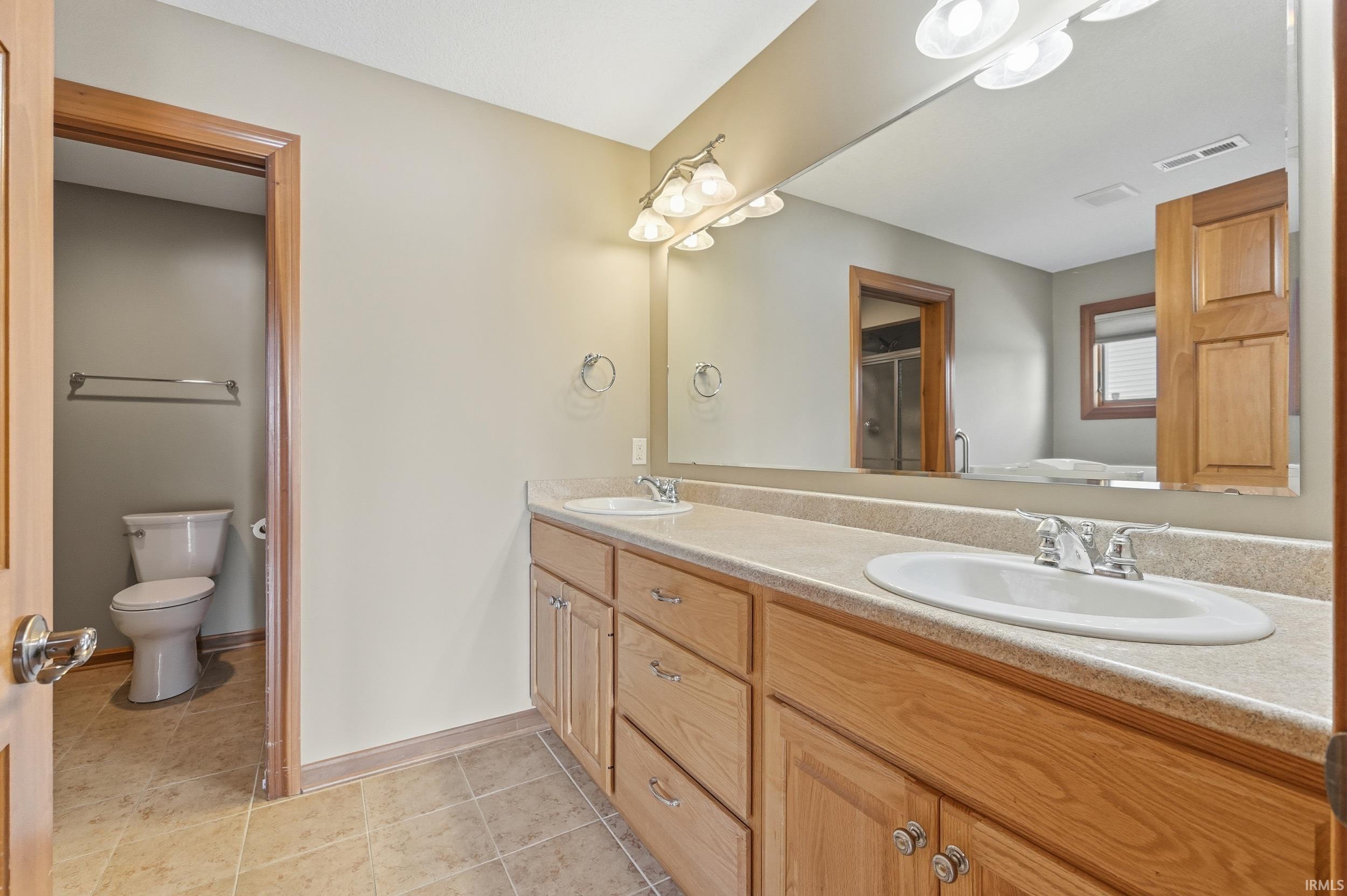 Bathroom with double vanity, a soaking tub, light tile patterned floors, and a shower stall
