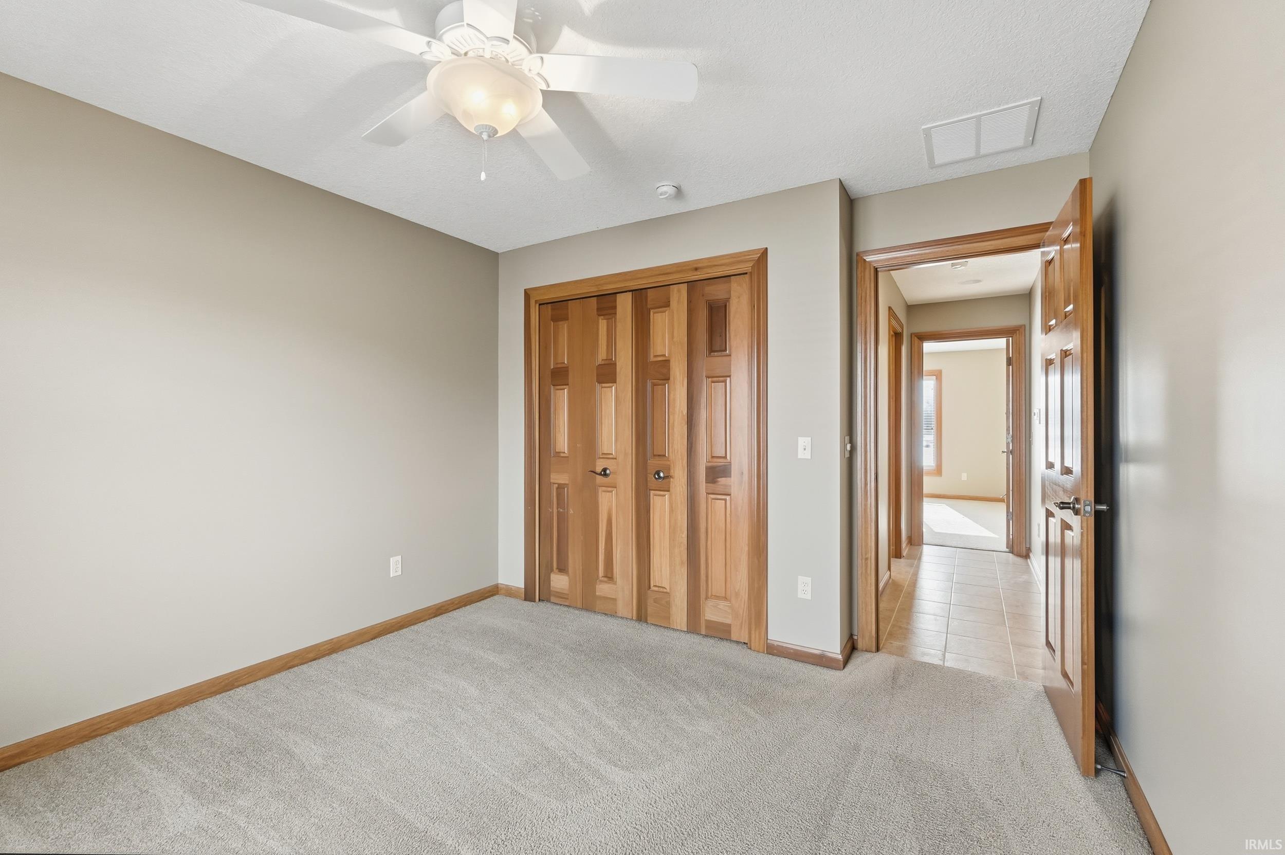 Unfurnished bedroom with light carpet, a closet, and a ceiling fan