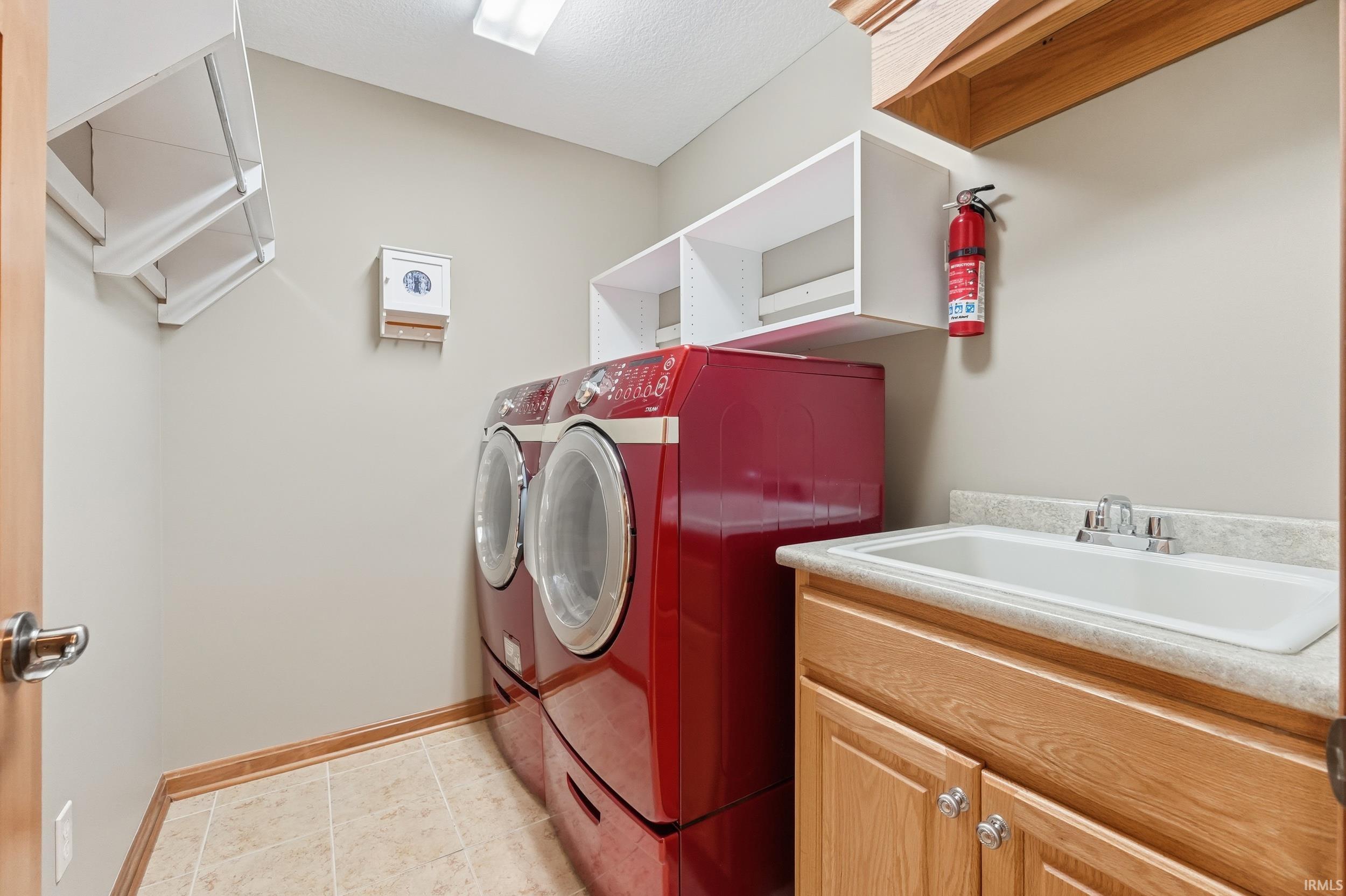Washroom with washer and dryer and light tile patterned floors