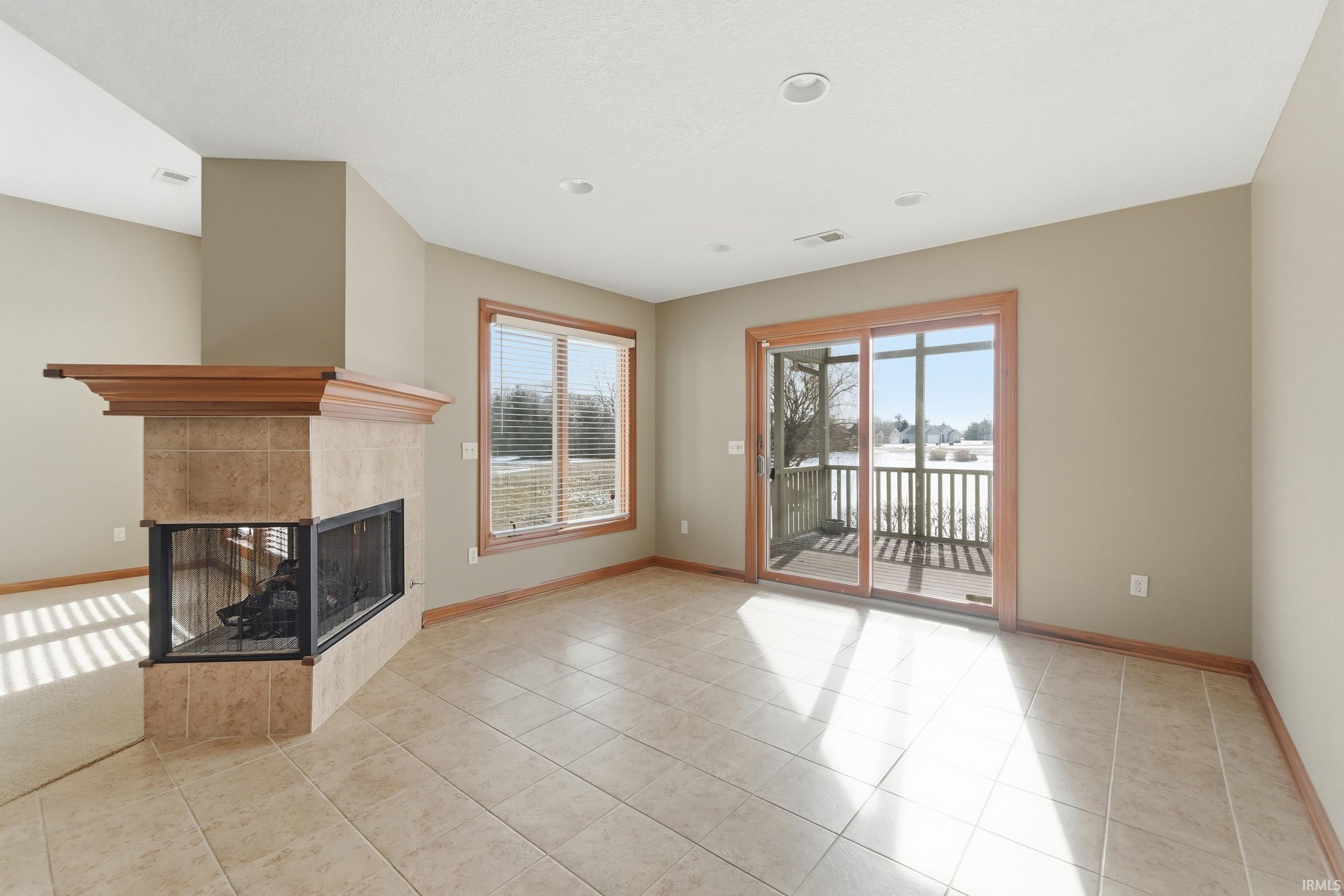 Unfurnished living room featuring a fireplace, healthy amount of natural light, and light tile patterned flooring