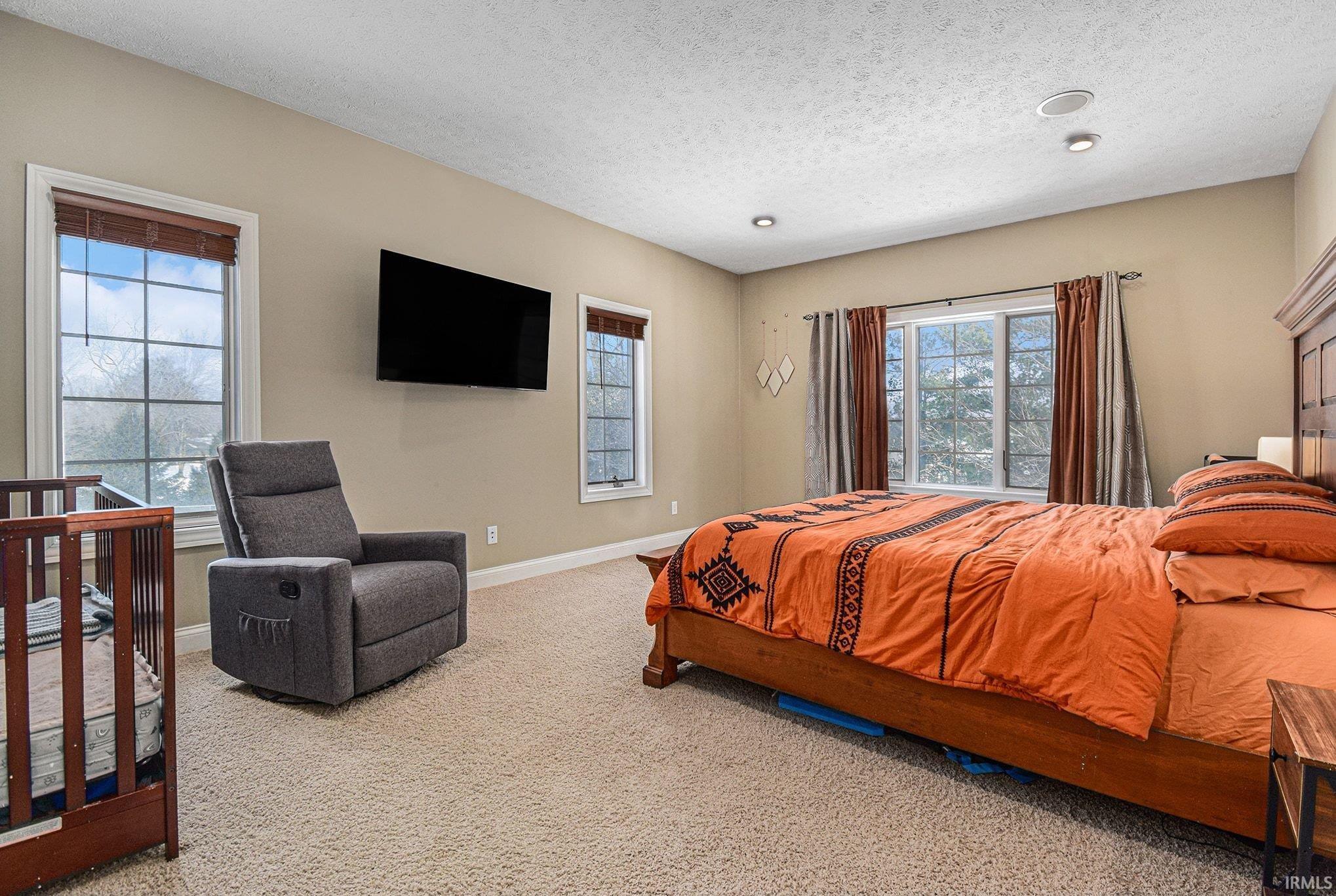 Carpeted bedroom with a textured ceiling and a crib