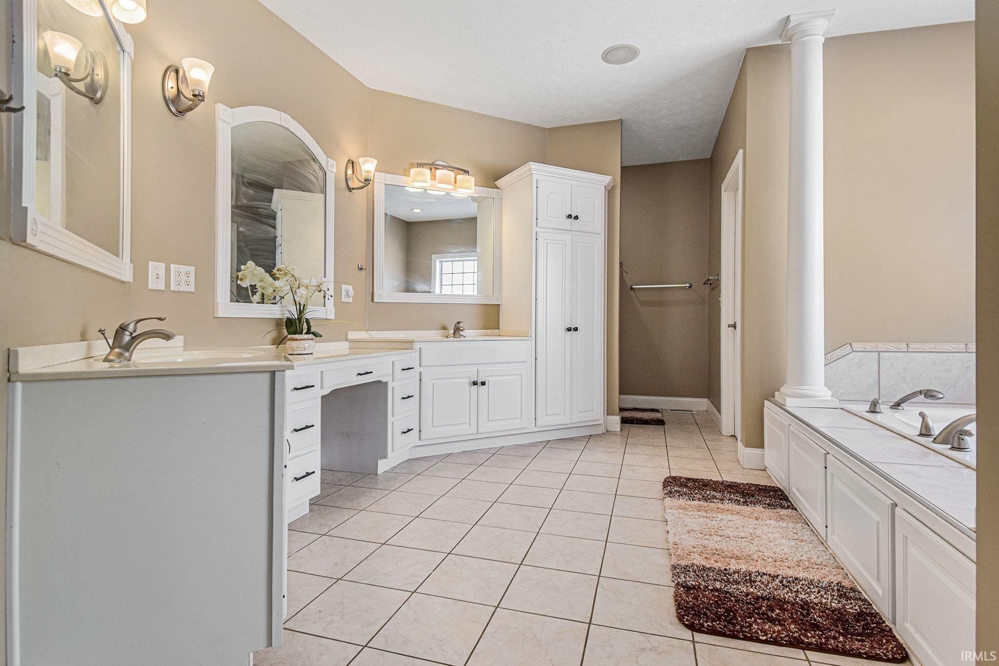 Bathroom featuring double vanity, a bath, and light tile patterned floors