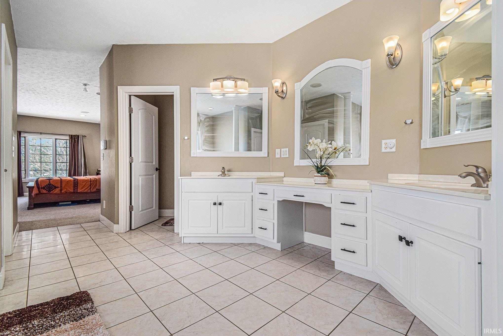 Ensuite bathroom with vanity and light tile patterned floors