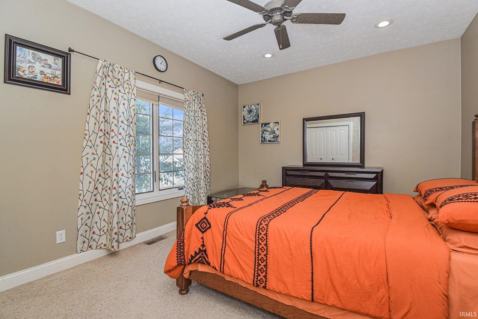 Bedroom featuring carpet, a textured ceiling, and a ceiling fan