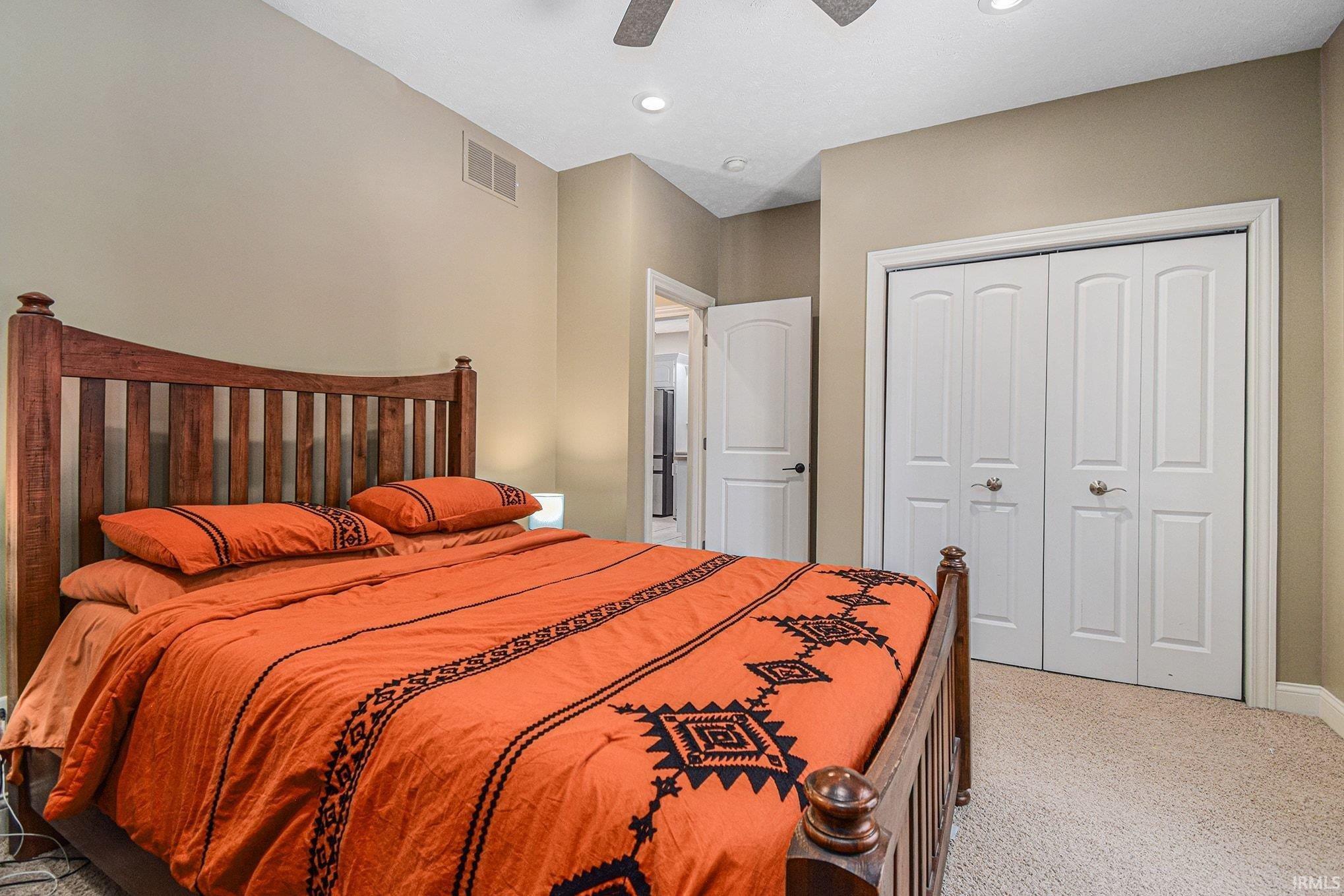 Bedroom featuring a closet, light carpet, and ceiling fan